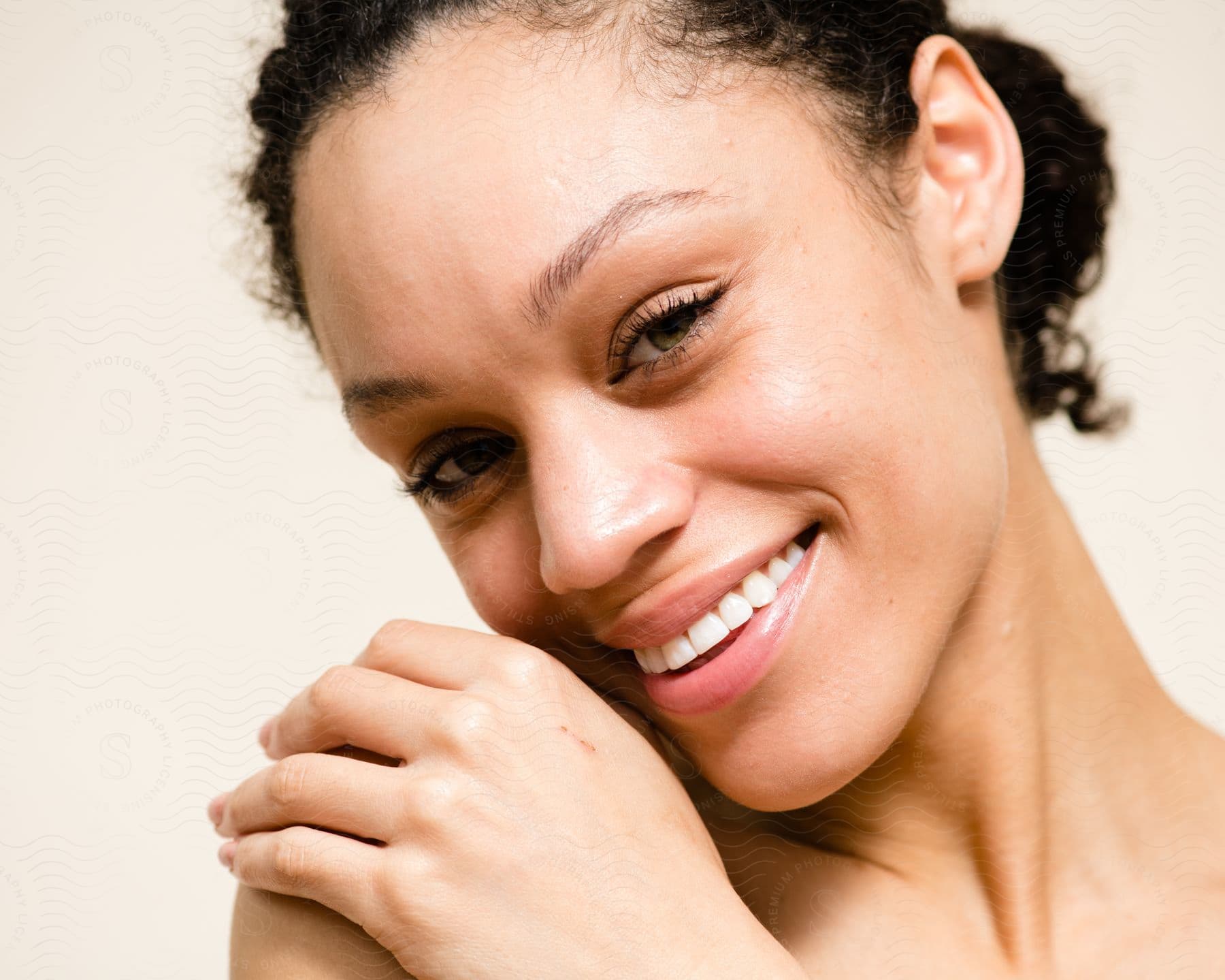 A woman smiling while tilting her head and holding her shoulder