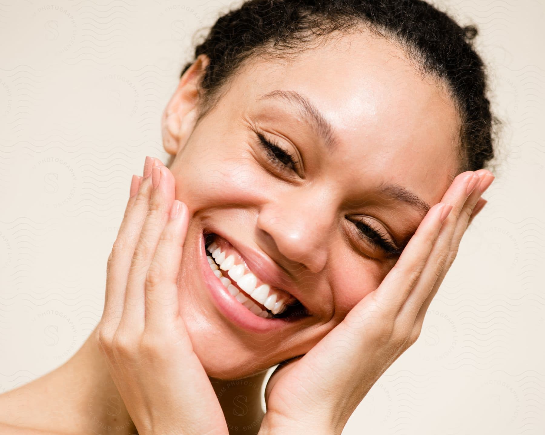 Joyful Woman Holding Face With Both Hands Against A Beige Background