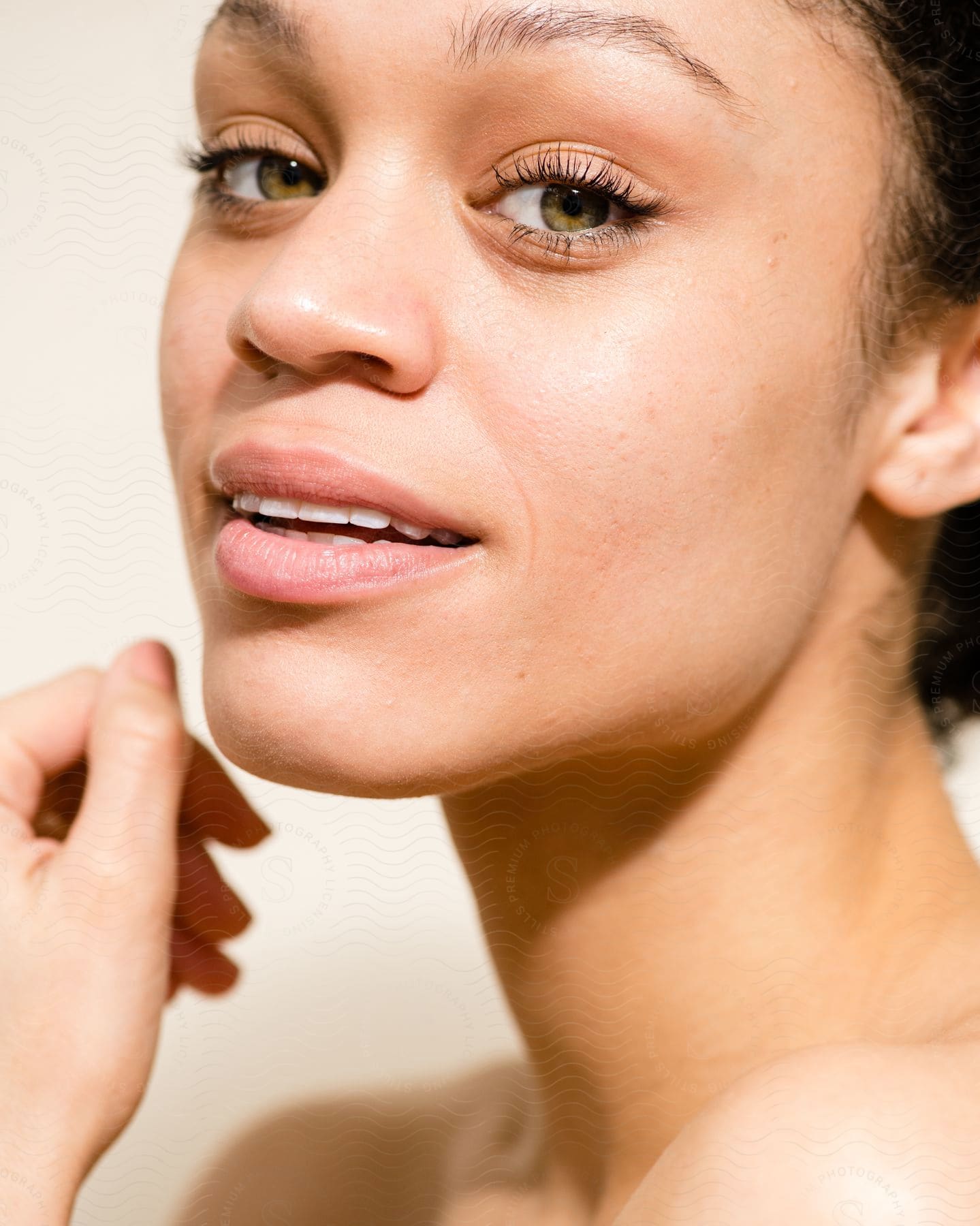 A woman with a faint smile almost touches her chin with her thumb