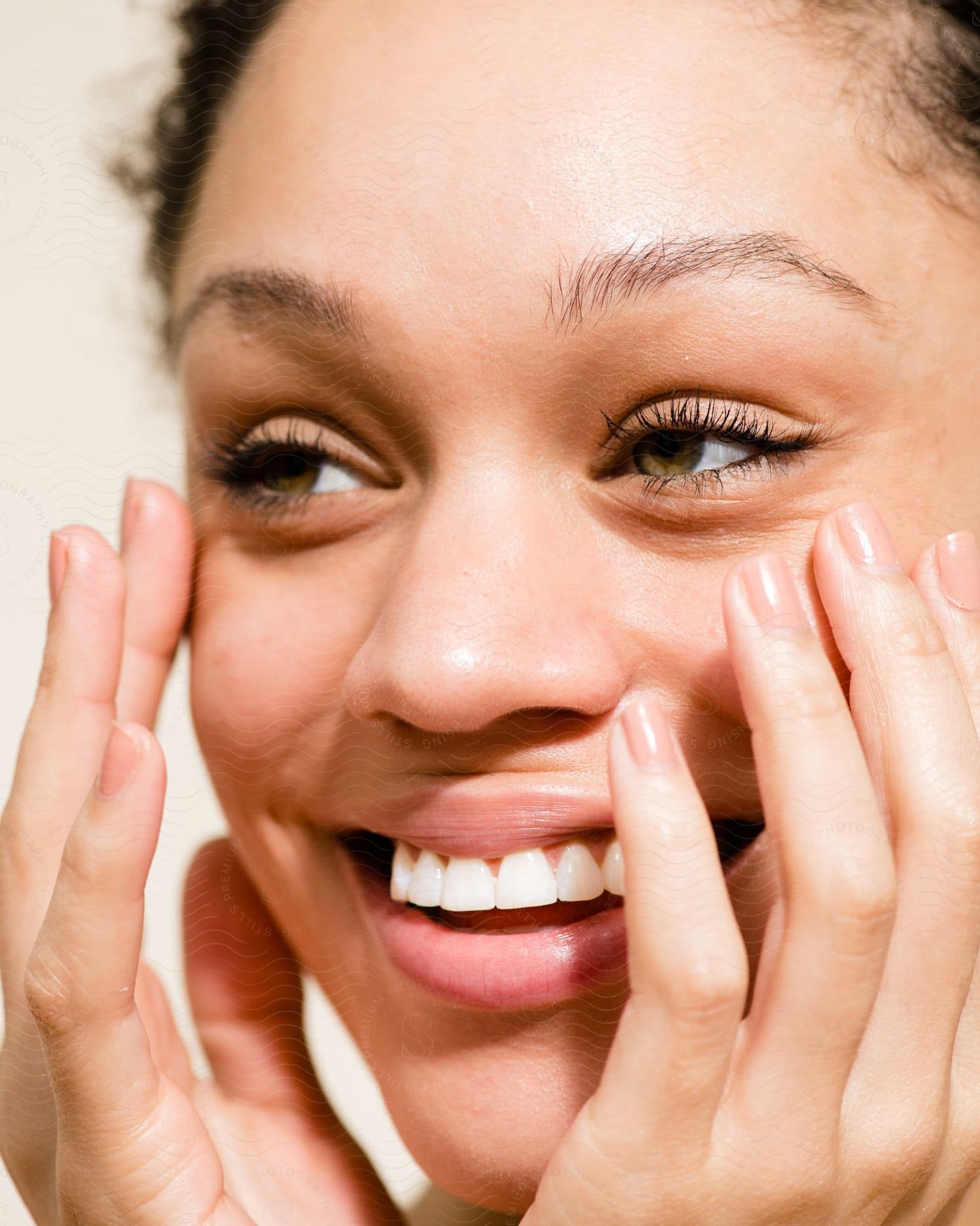 A woman smiling with her hands on her face