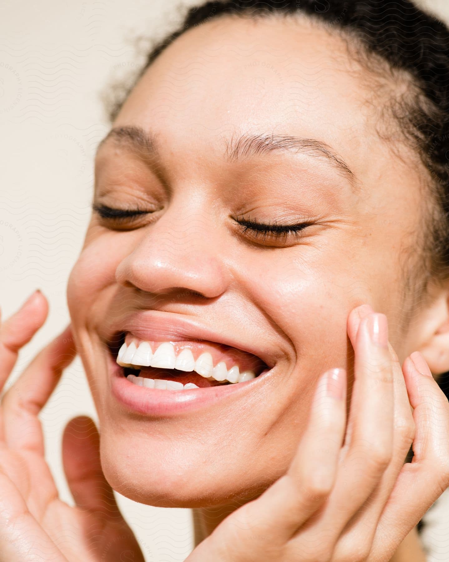 close-up of a lady smiling with eyes closed and fingers on both cheeks