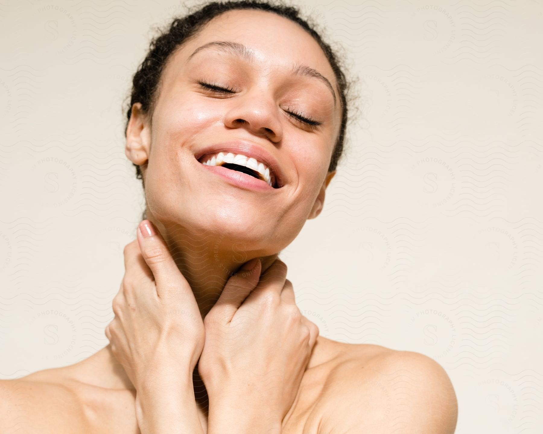 a woman smiling with her hands on her neck