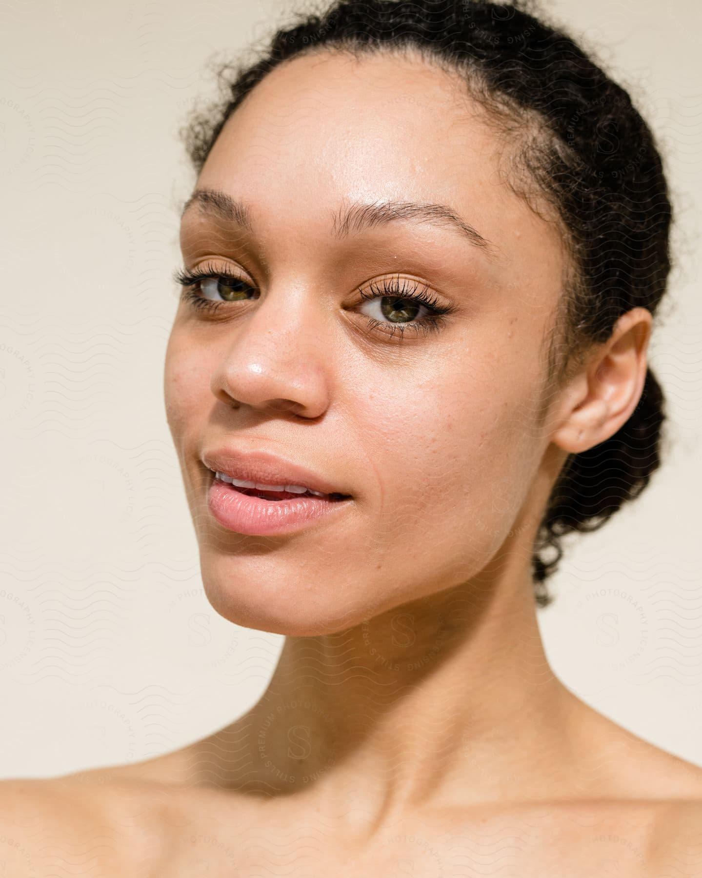 A portrait of a woman in a room modeling makeup.