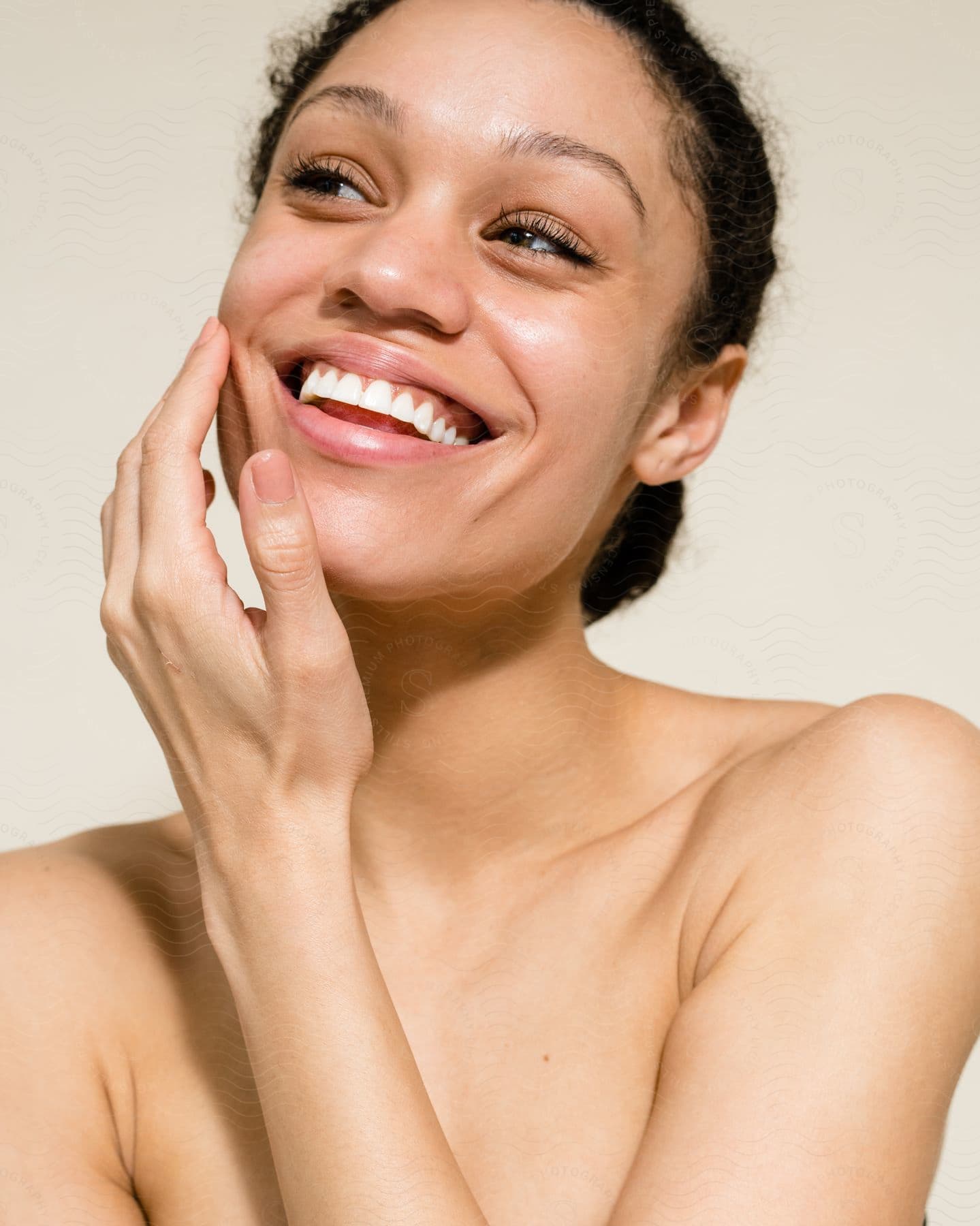 Woman smiles with her hand on her face as she looks to her side