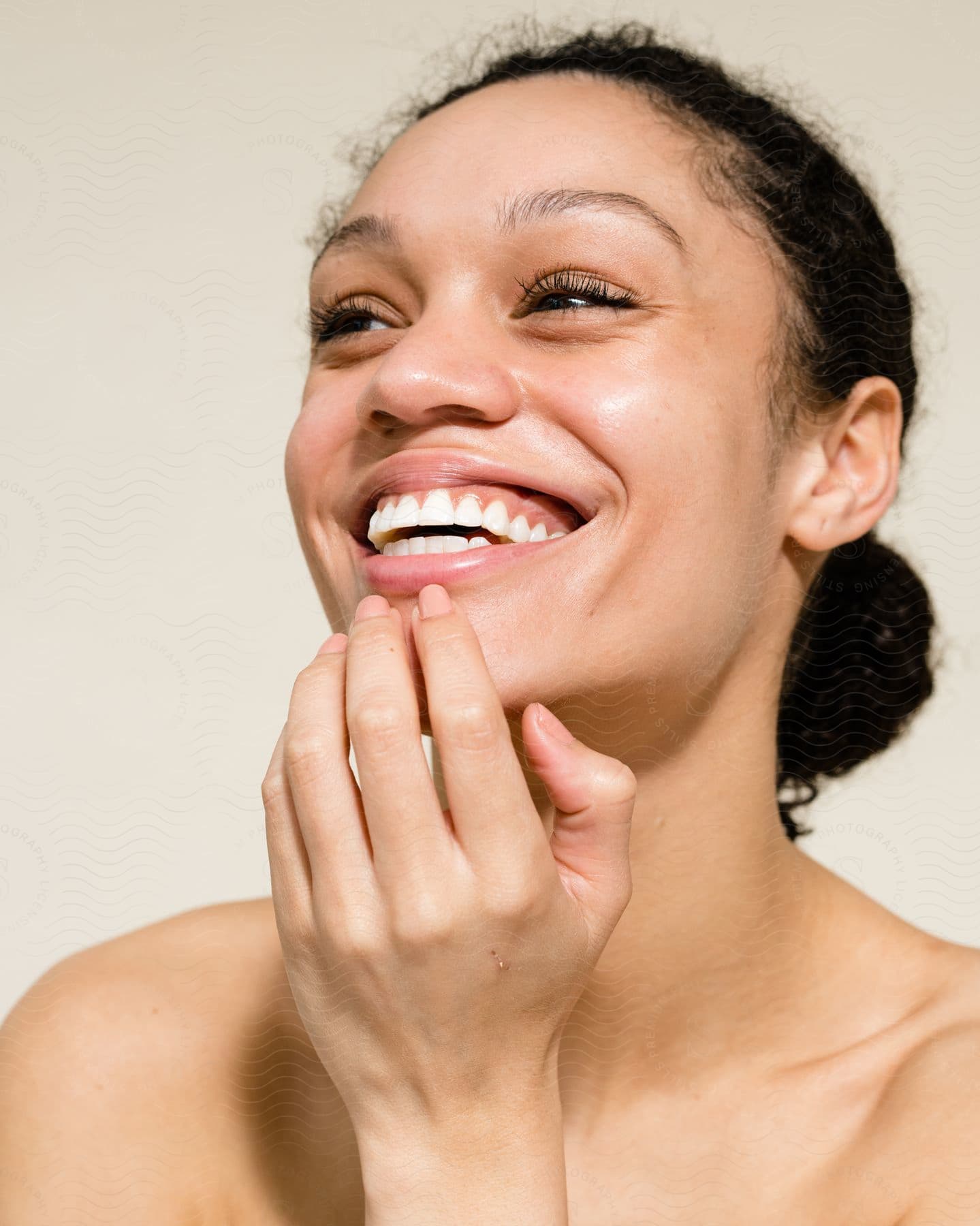 a multi racial woman smiling with her fingers on her lip