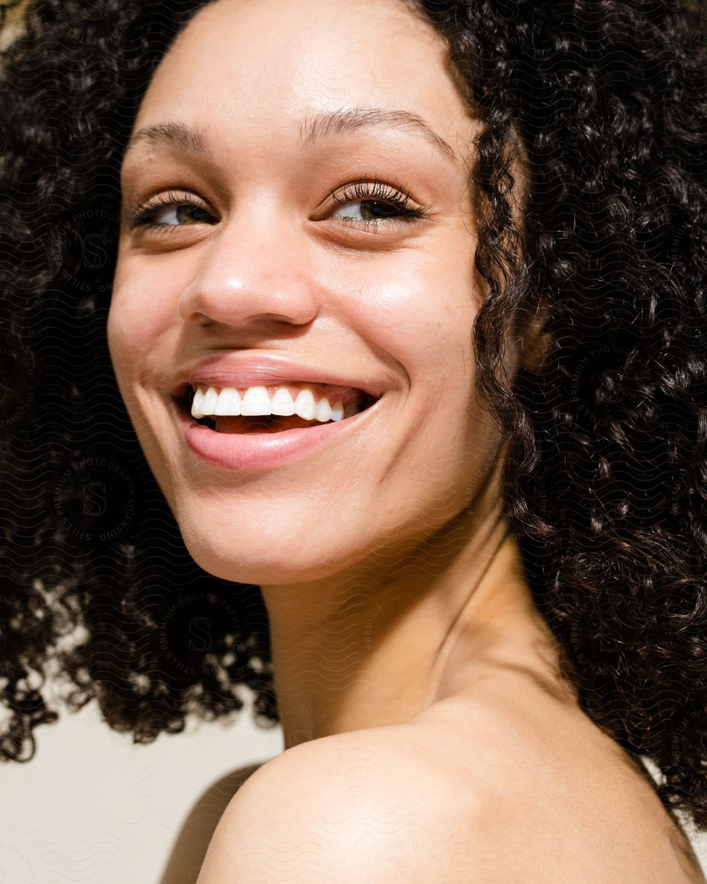 Close up of the face of a beautiful smiling model with curly hair