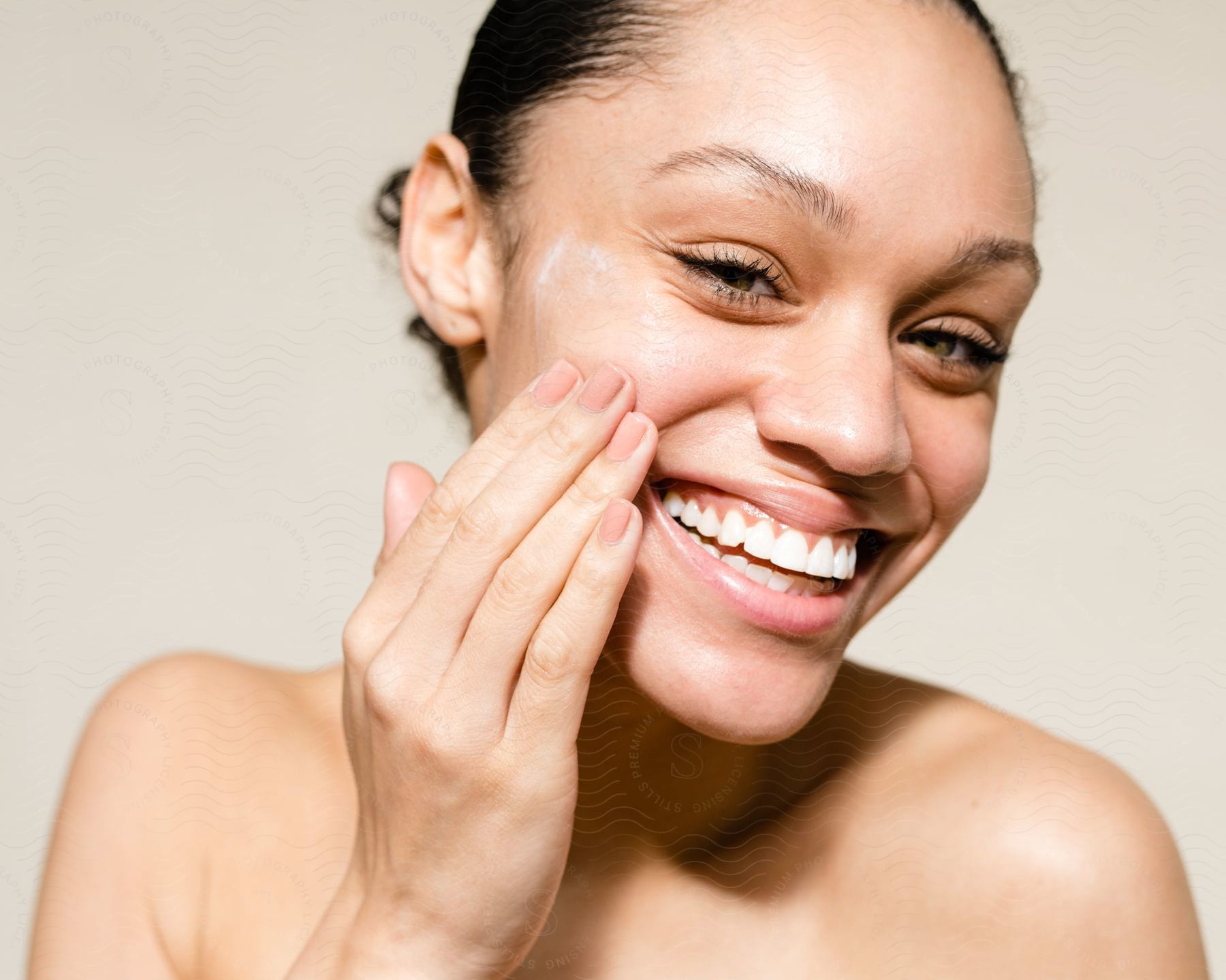 Woman laughing as she rubs cream on her cheek