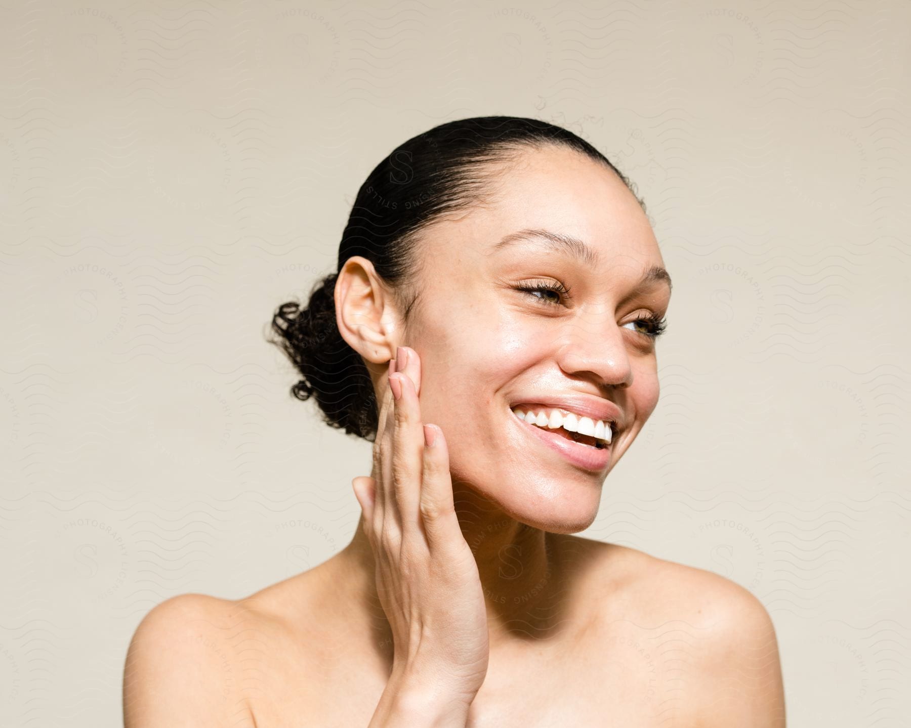 A woman smiling while touching her face