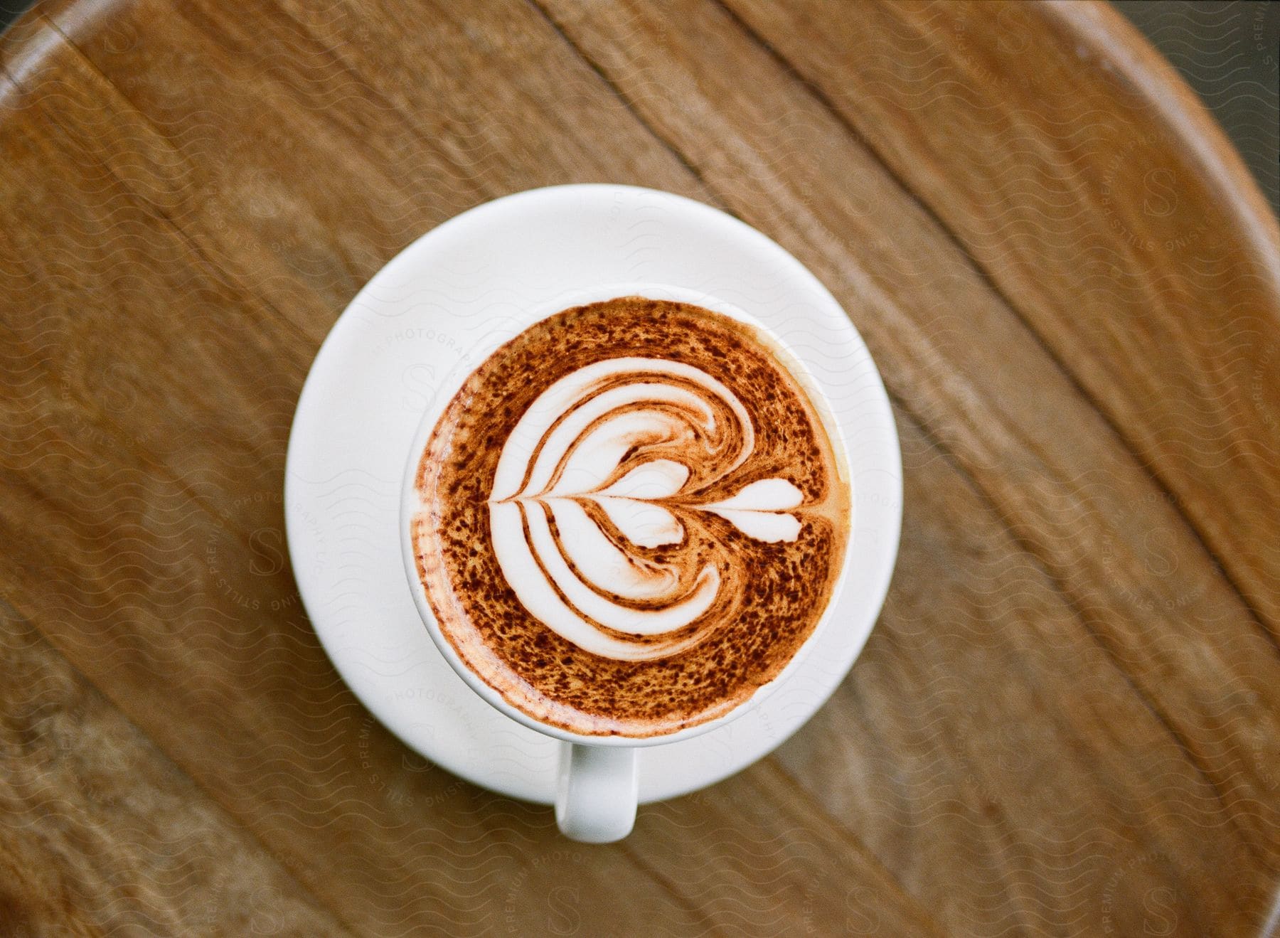 Cup with cappuccino decorated with heart design on a wooden table