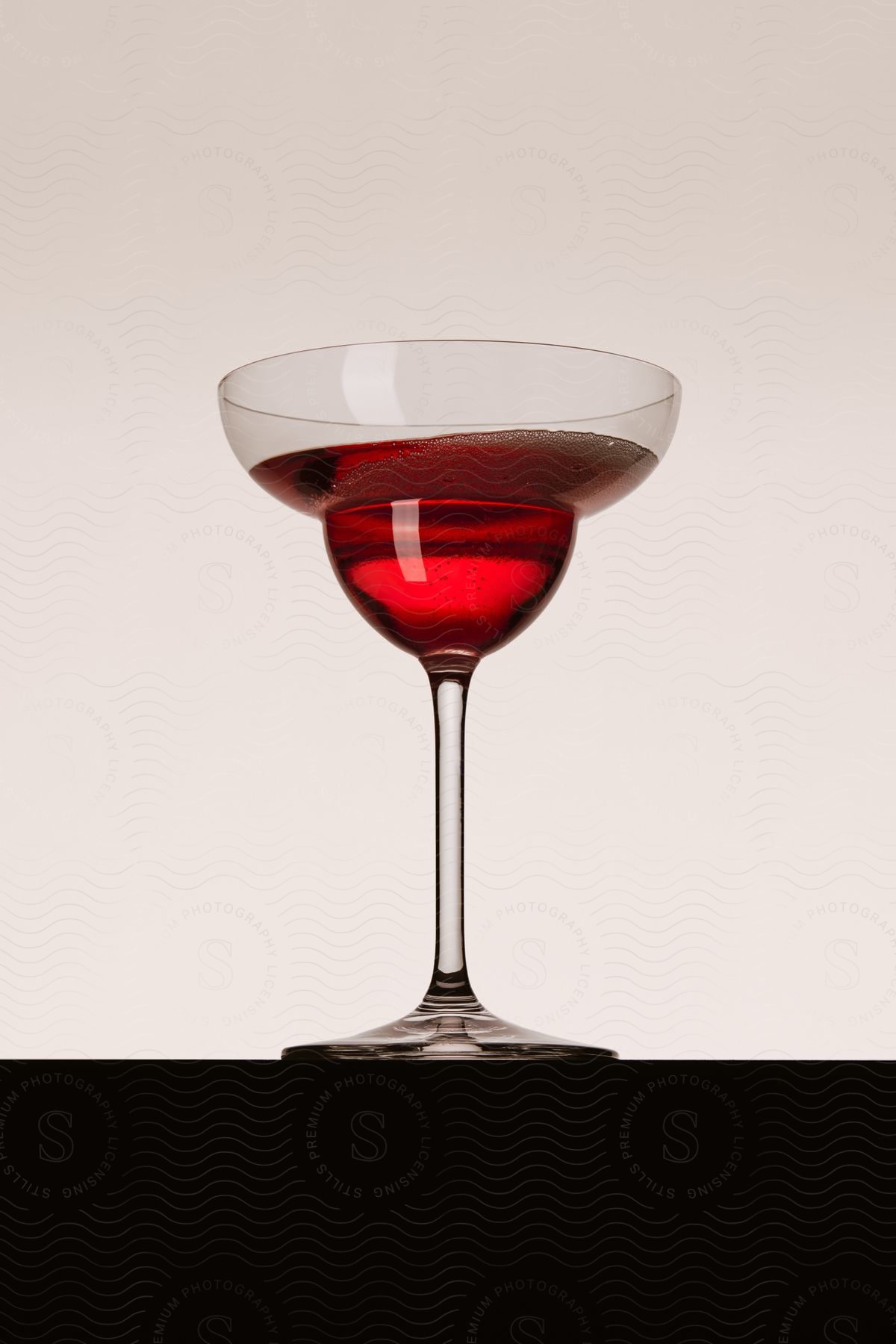 A red liquid in a margarita cocktail glass