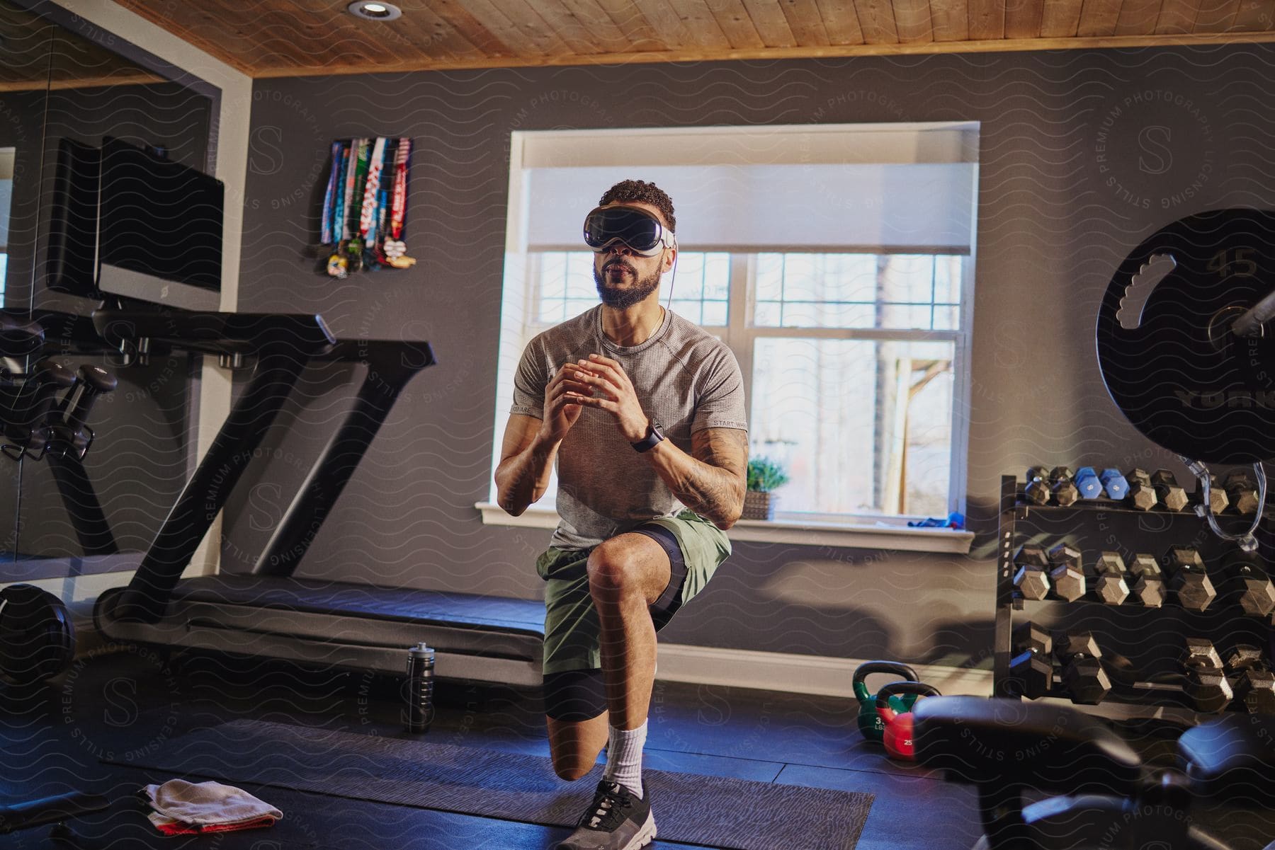 A person wearing VR goggles is performing lunges in a well-equipped home gym