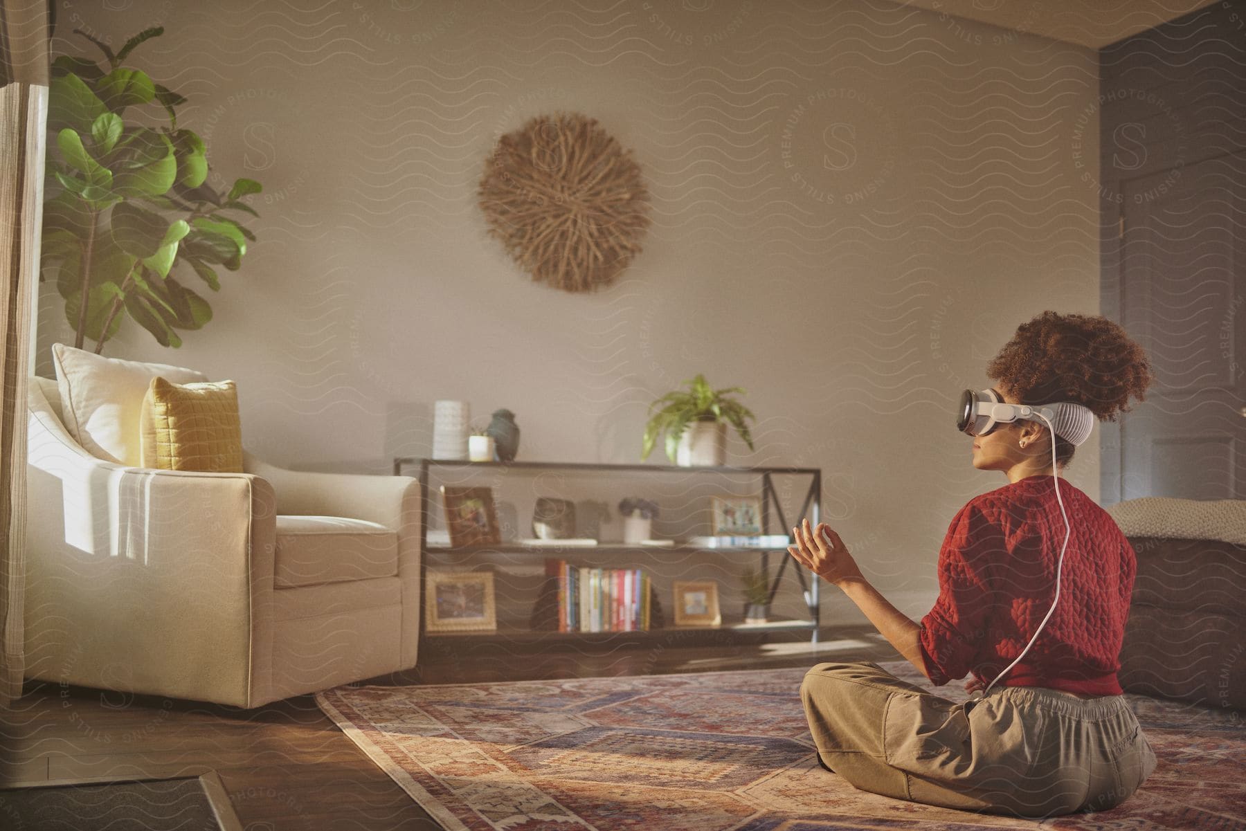 A woman is sitting on the floor of a living room and is wearing virtual reality glasses on her face