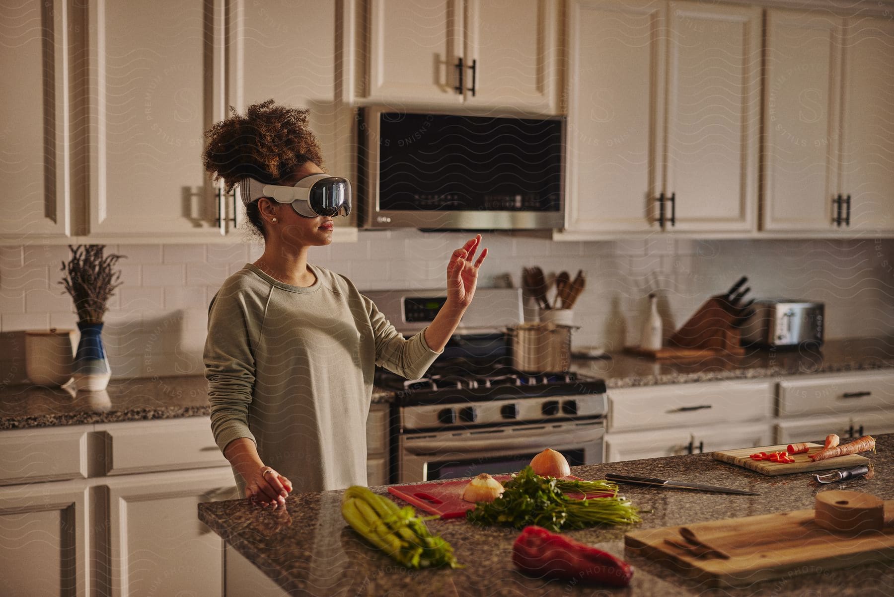 A black woman uses a VR headset while chopping fresh vegetables on a kitchen counter.