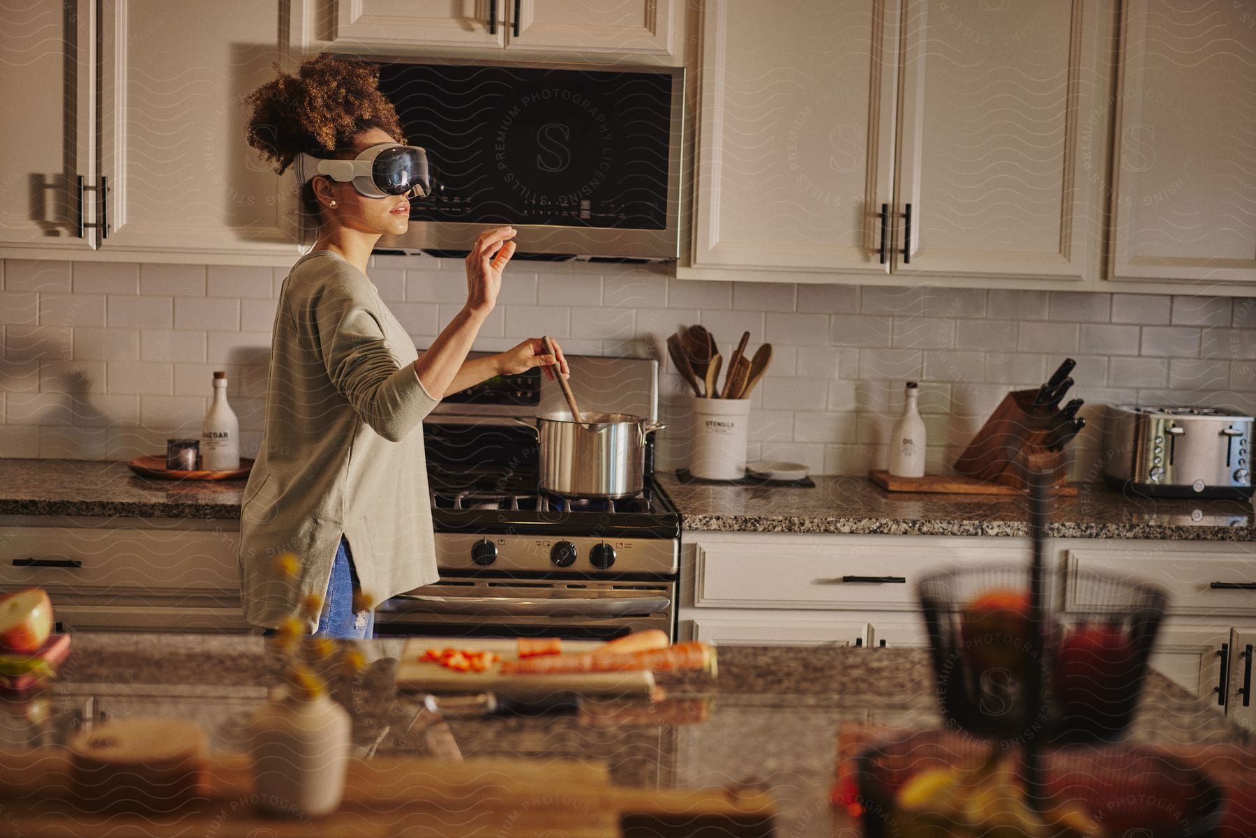 Woman wearing virtual reality headset while cooking in a modern kitchen.