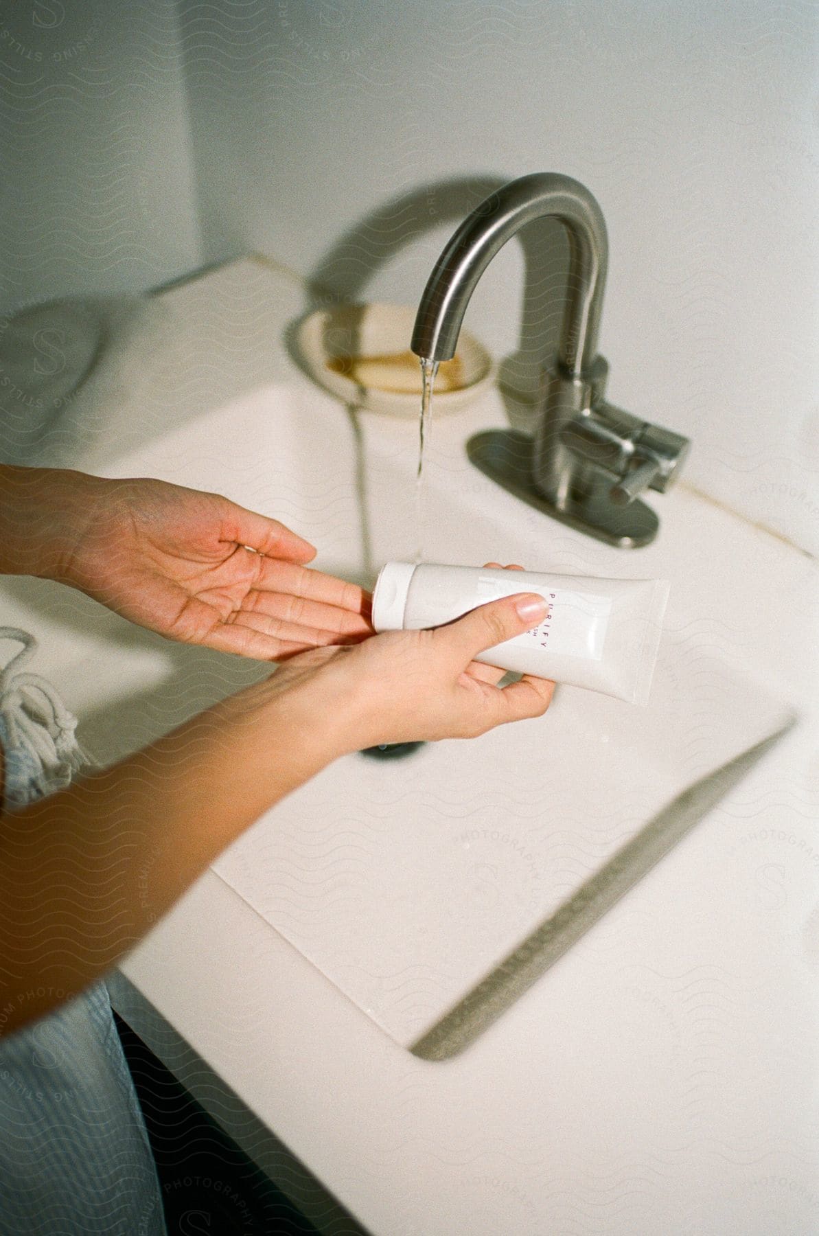 woman's hands as she applies cream in the bathroom basin,