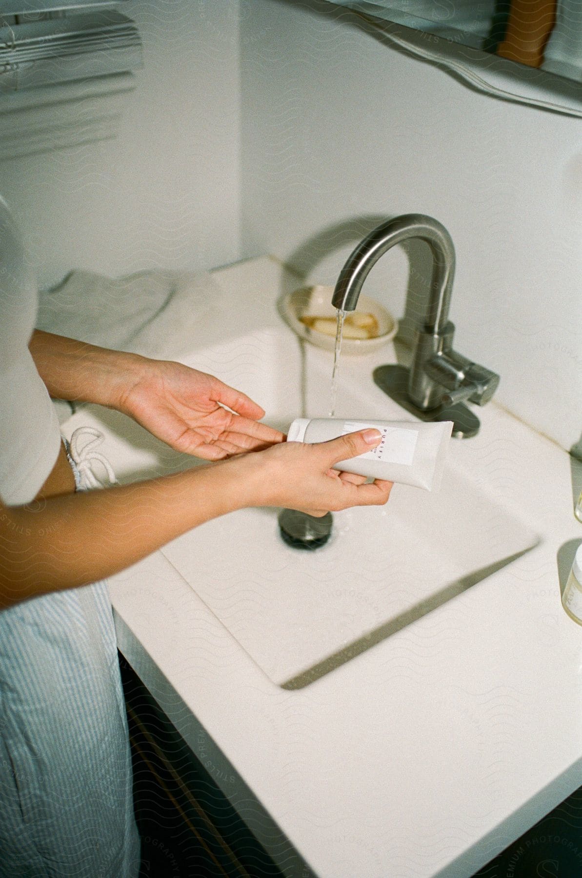 User Close up of woman’s hand applying cream in the bathroom basin