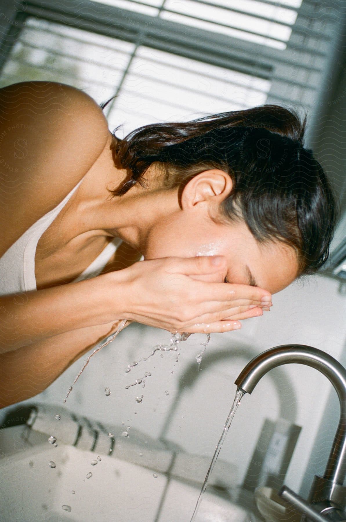 Stock photo of a woman washing makeup off of her face.