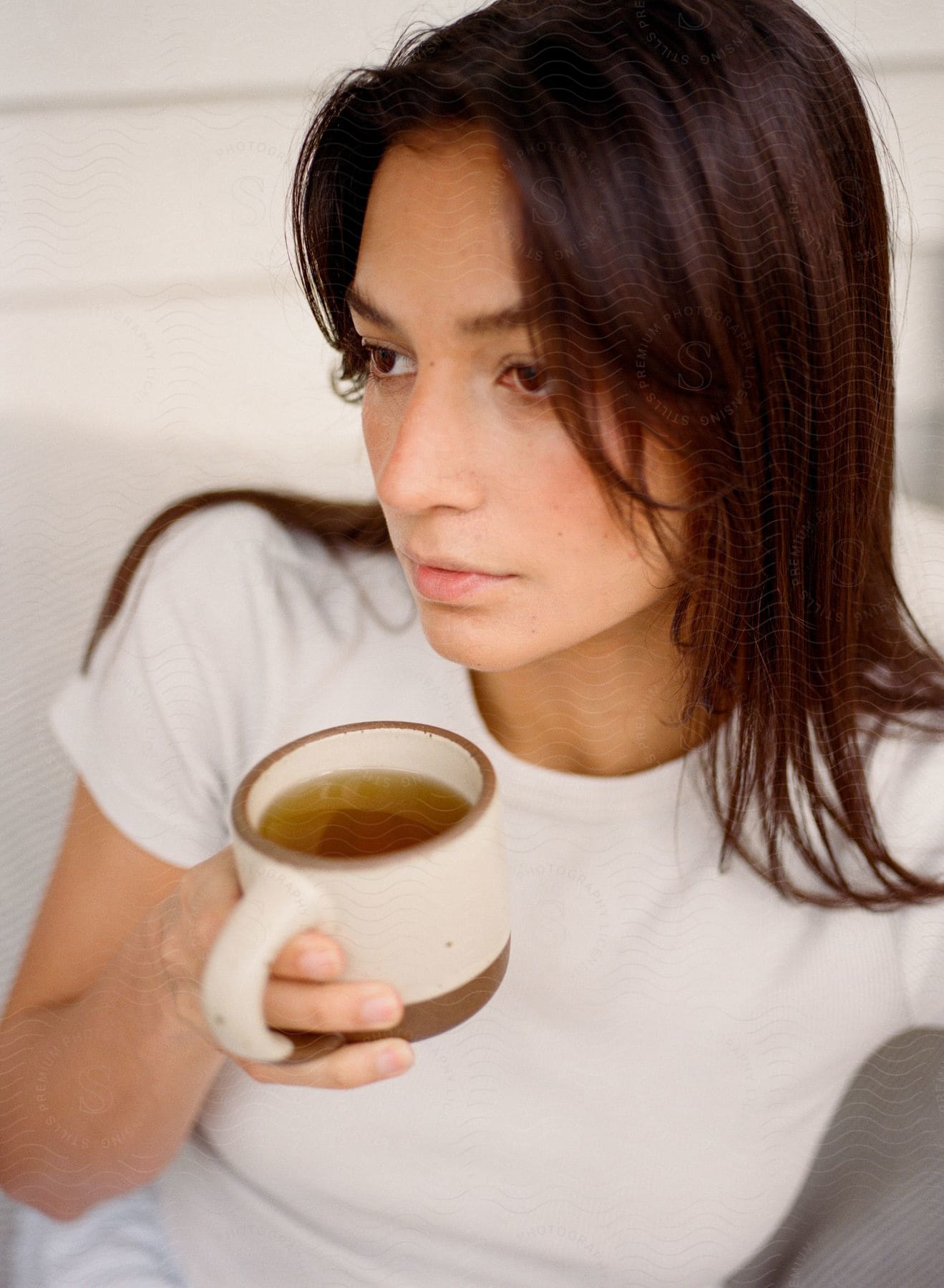 Young woman in a white t-shirt holding a cup of tea.