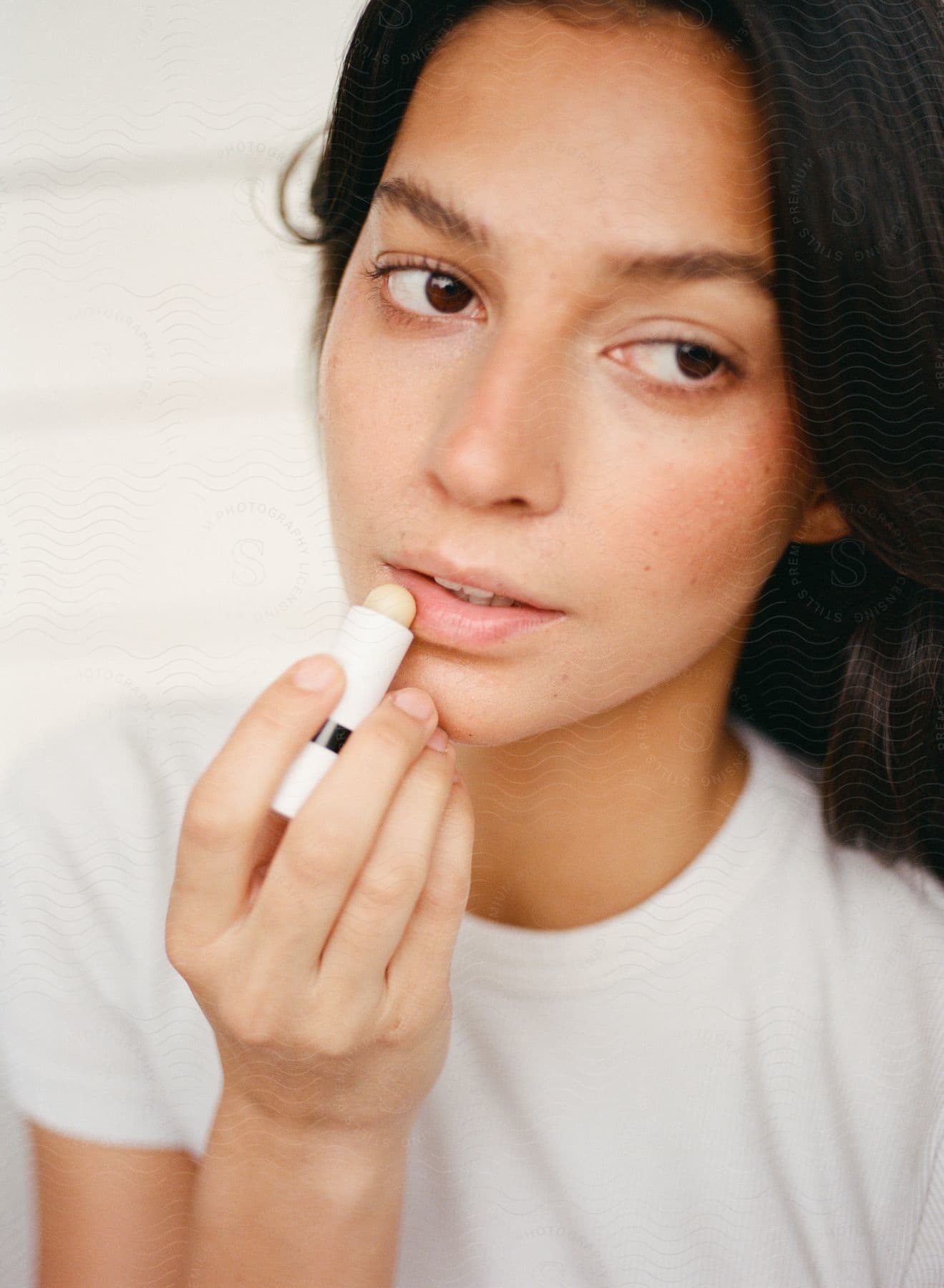 Woman is putting lip balm on her lips