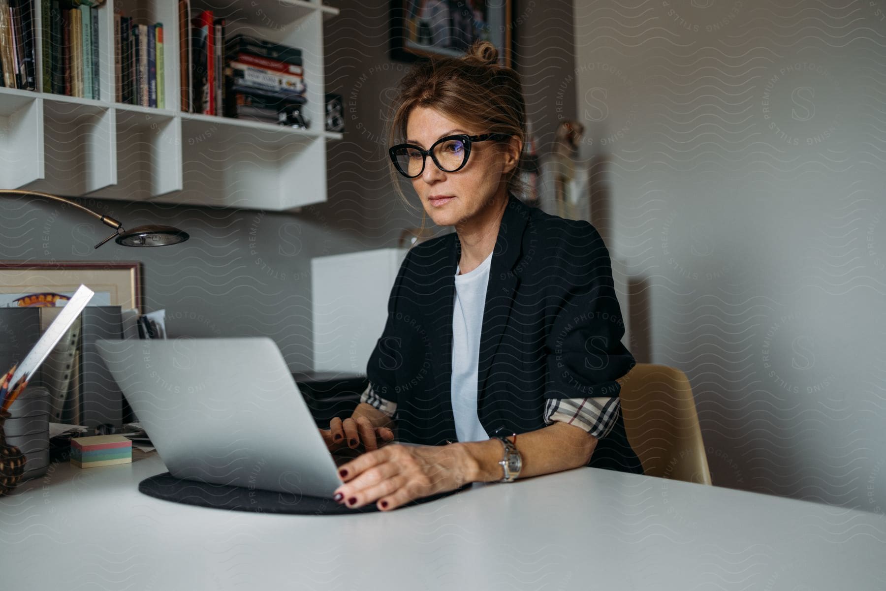 Woman with prescription glasses sitting at an office desk in front of her laptop