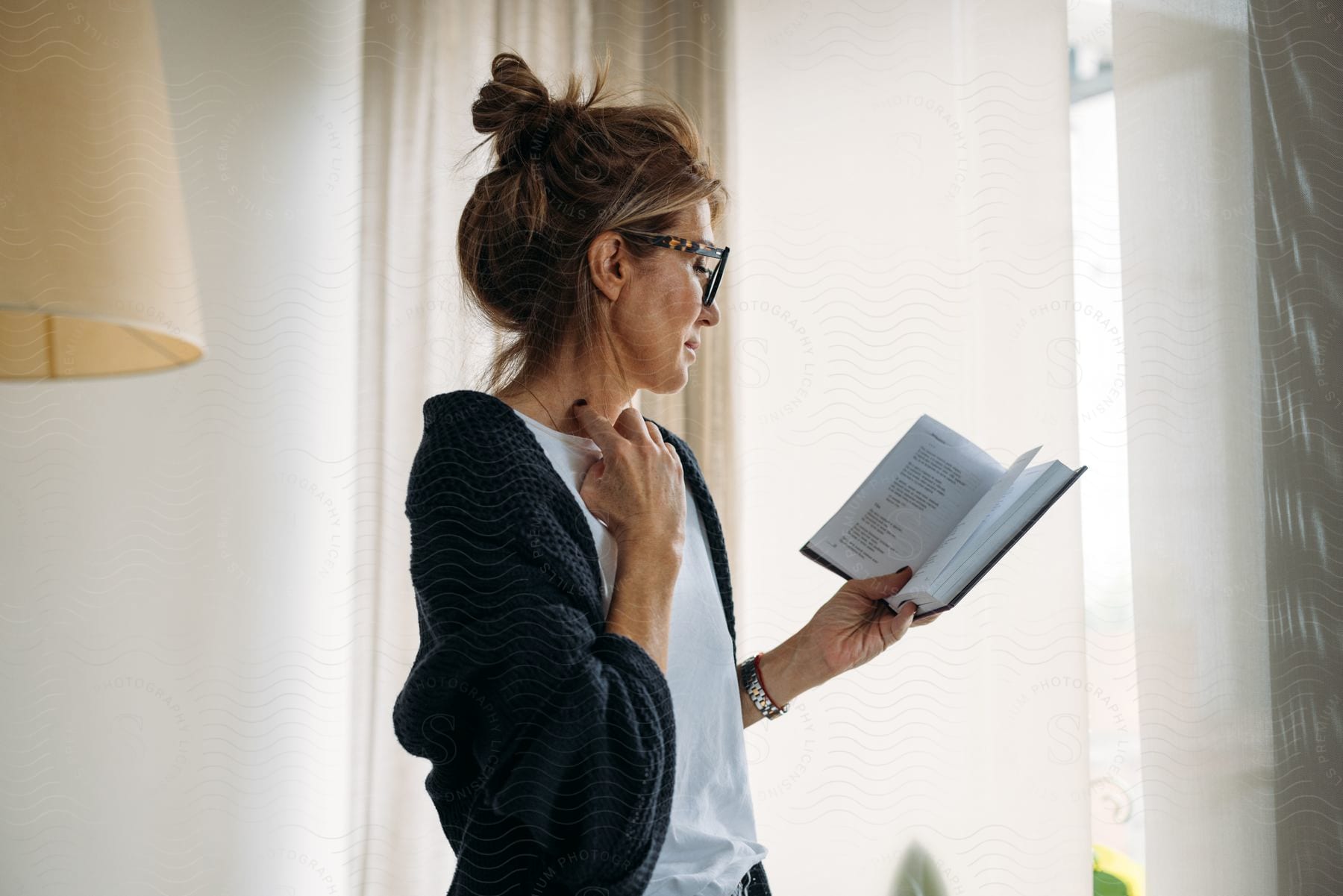 Woman is standing in her living room reading a book