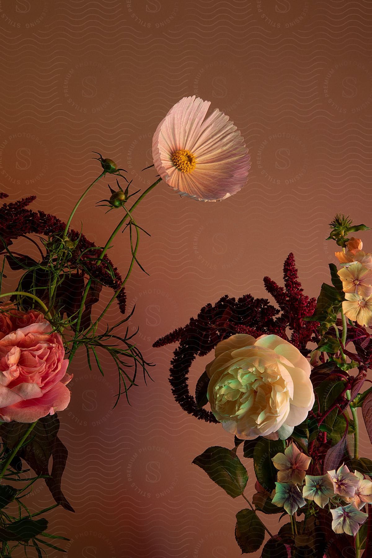 A variety of flowers separated in two arrangements facing each other in a dusty pink room.