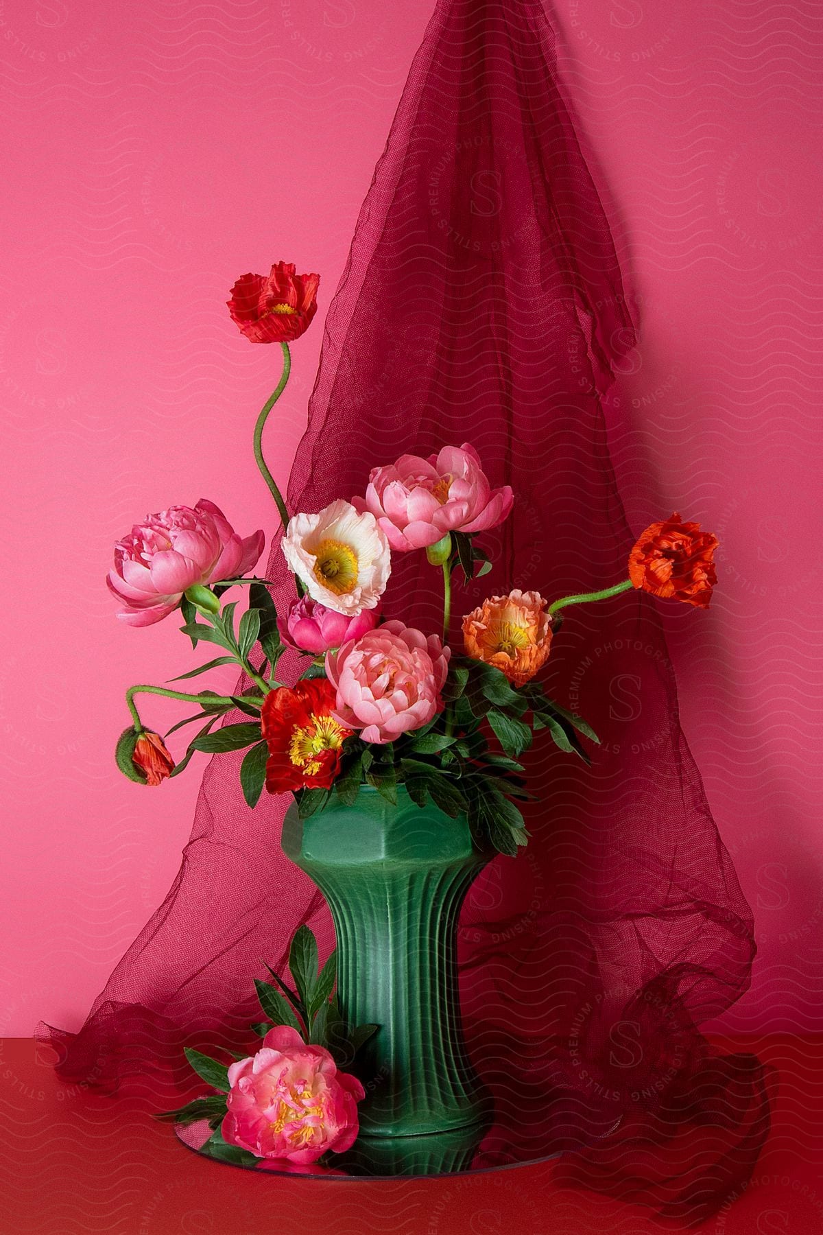 Stock photo of a flower plant with different flower combination in a vase against a pink background