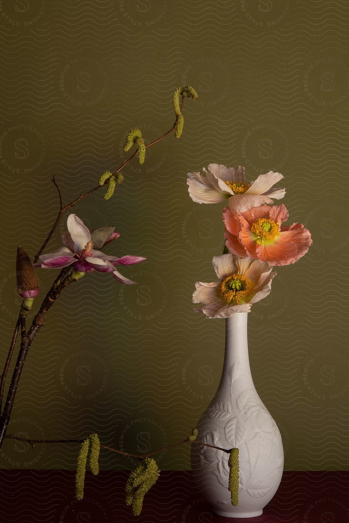 White ceramic vase with flowers and buds and an orchid next to it