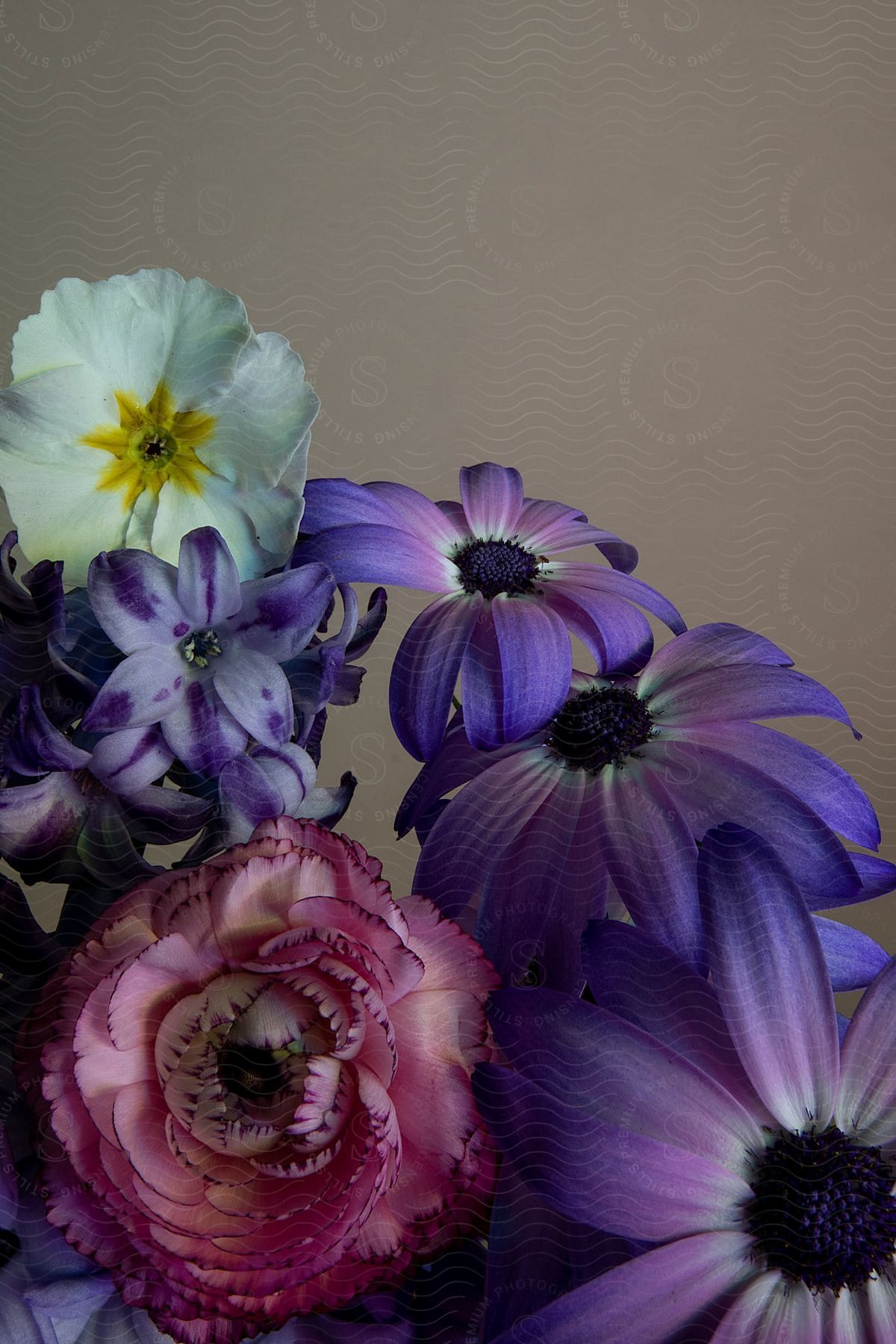 A Purple Flower Mixed With Other Flowers Against A Brown Background