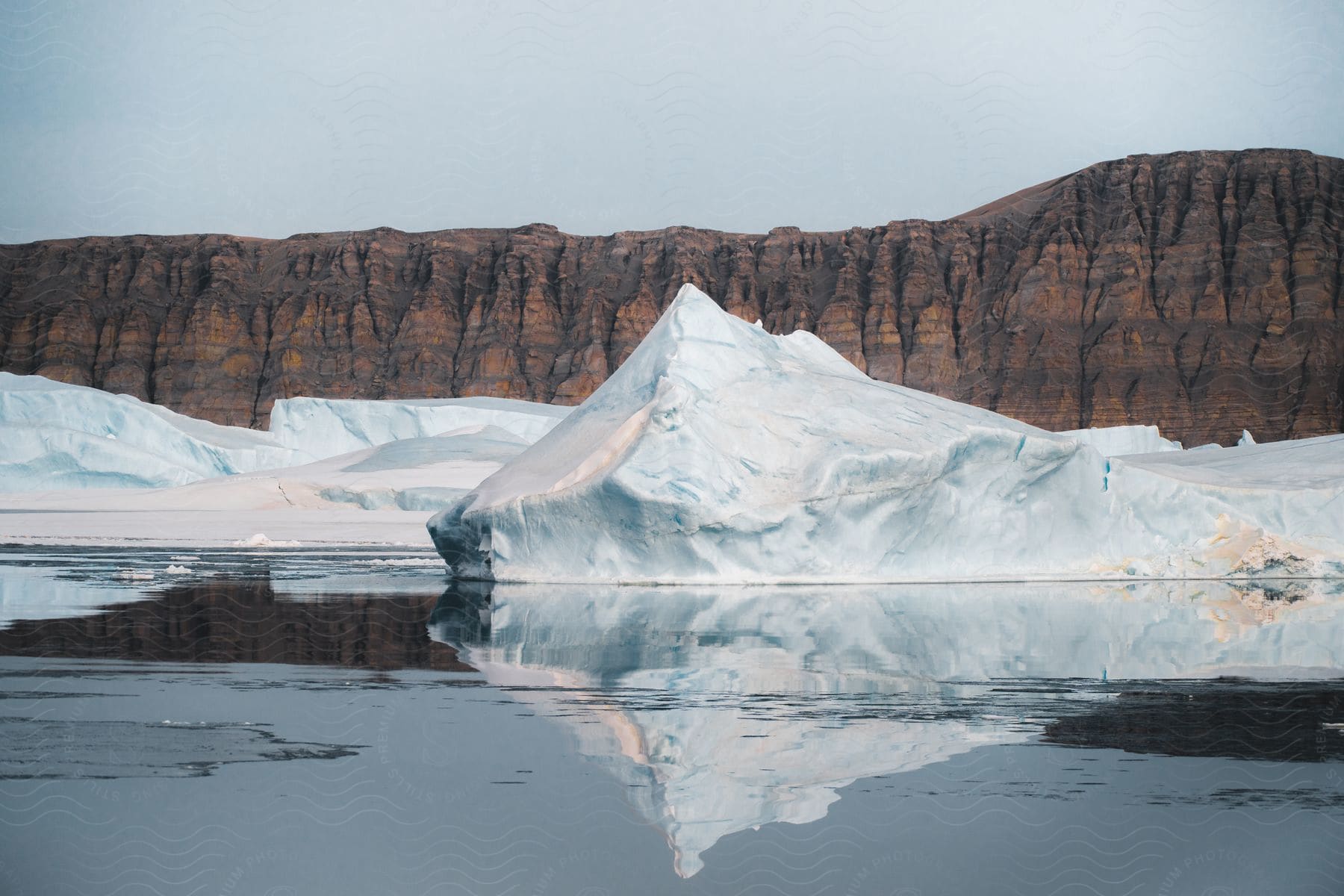 icebergs floating in front of a rocky cliff