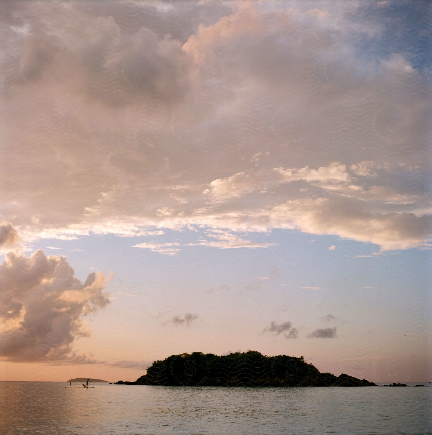 Silhouettes of people standing in the water off the shore of an island