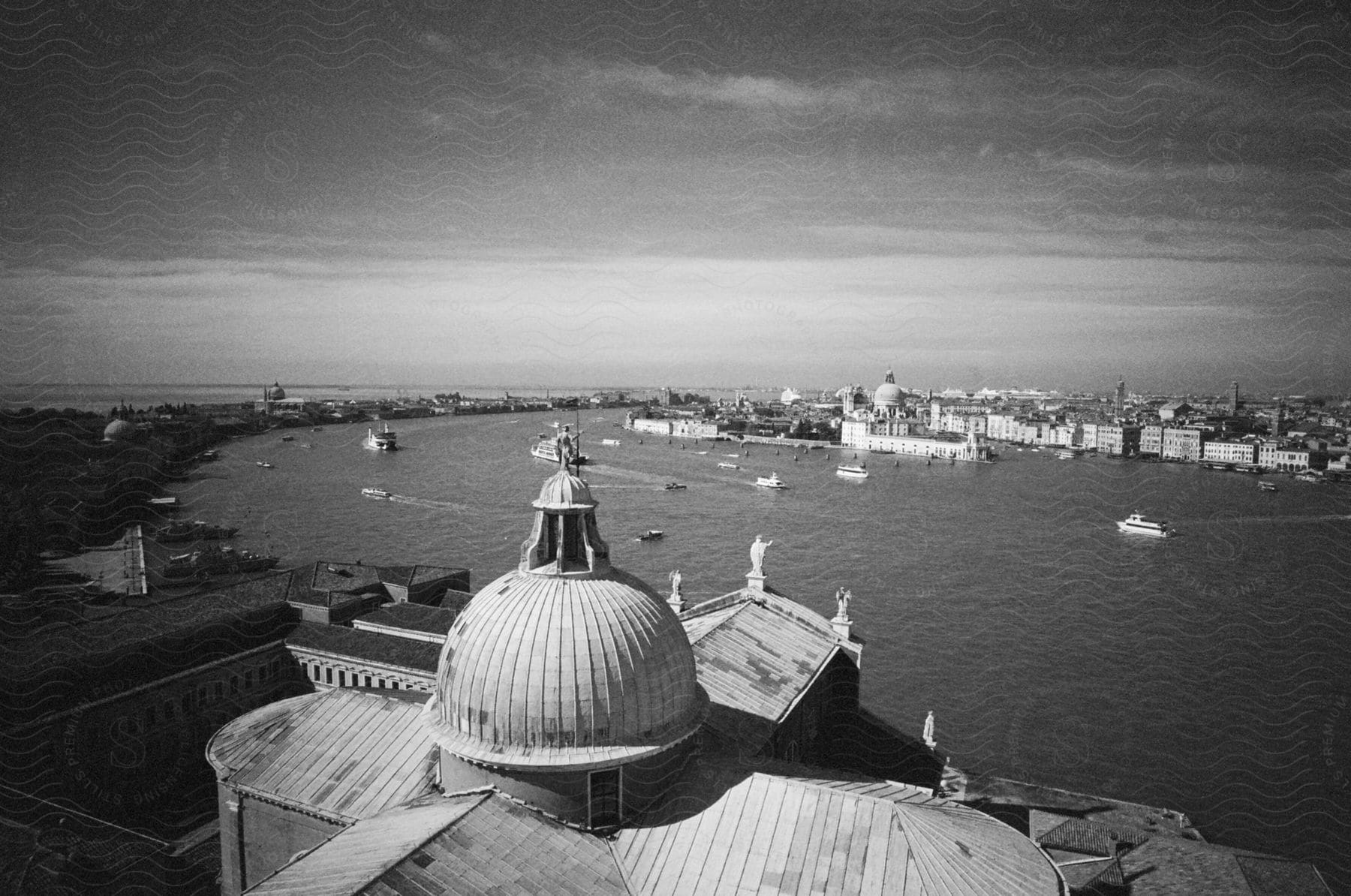 Domed building along the coast as boats sail with city buildings across the river