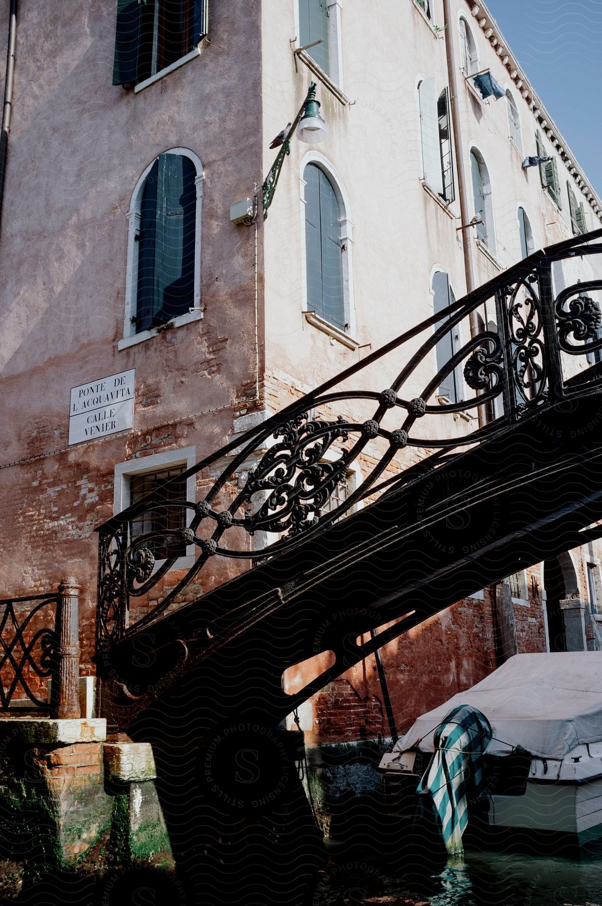 A covered motorboat in the canal under an iron  pedestrian bridge in Venice