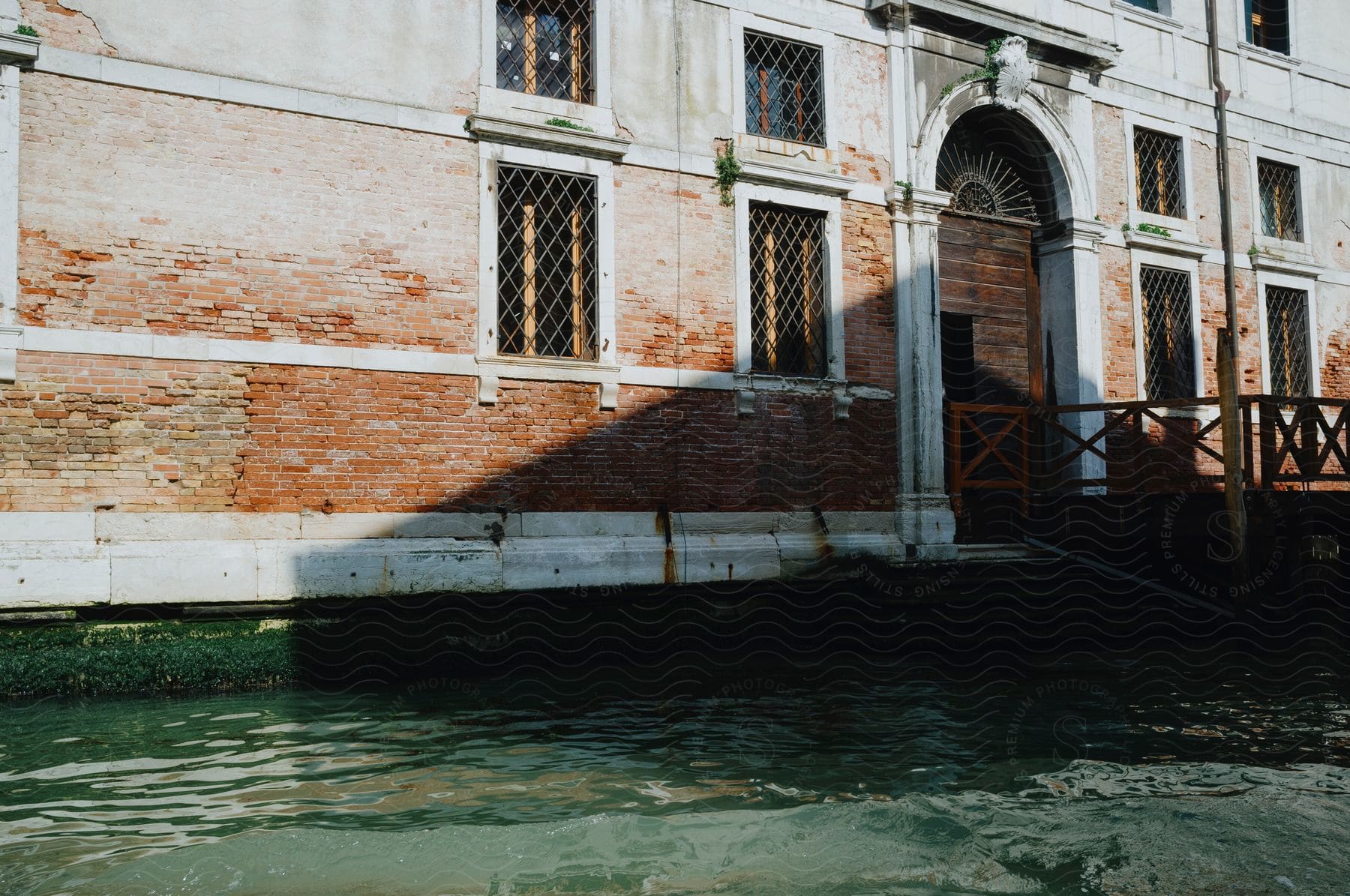 A weathered building with brick walls and ornate windows faces a canal, illustrating the unique architecture and waterways of Venice.