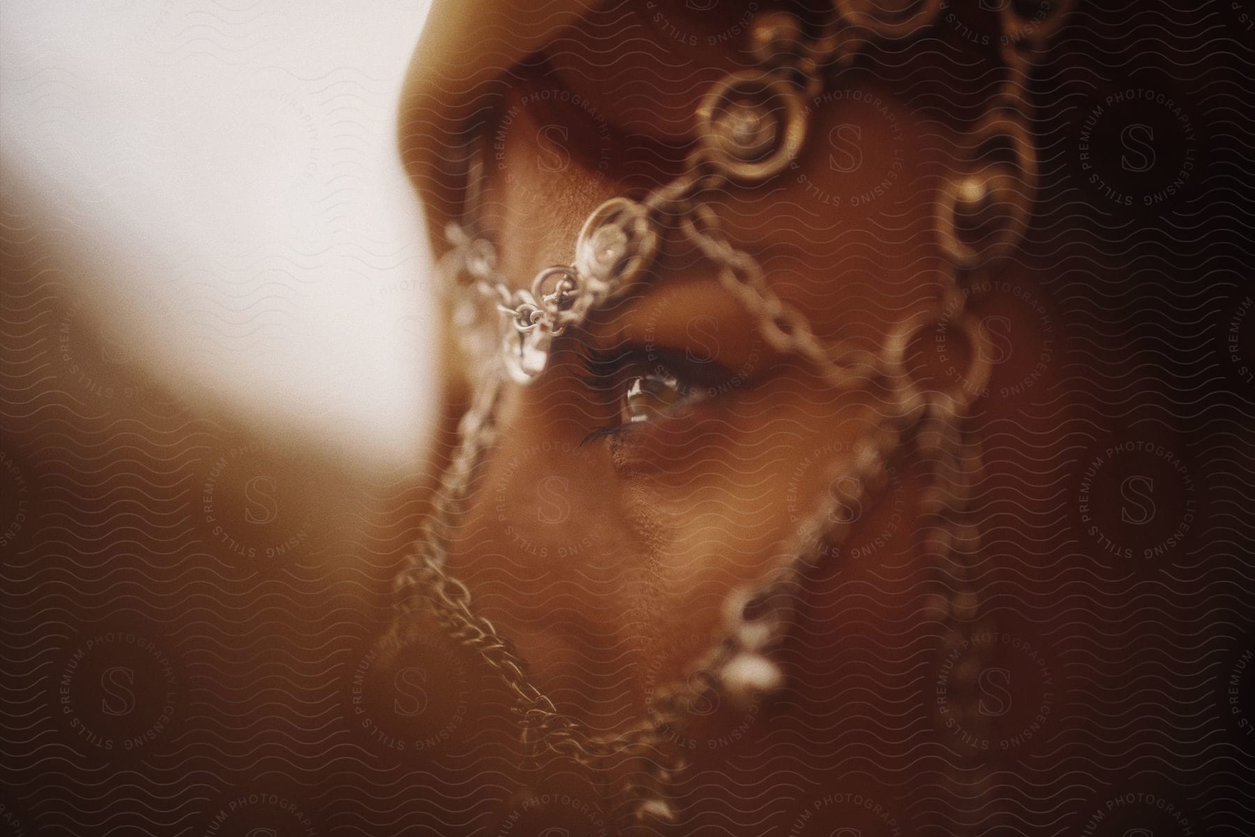 Close up of a woman's eye with chain jewelry partially obscuring her face.