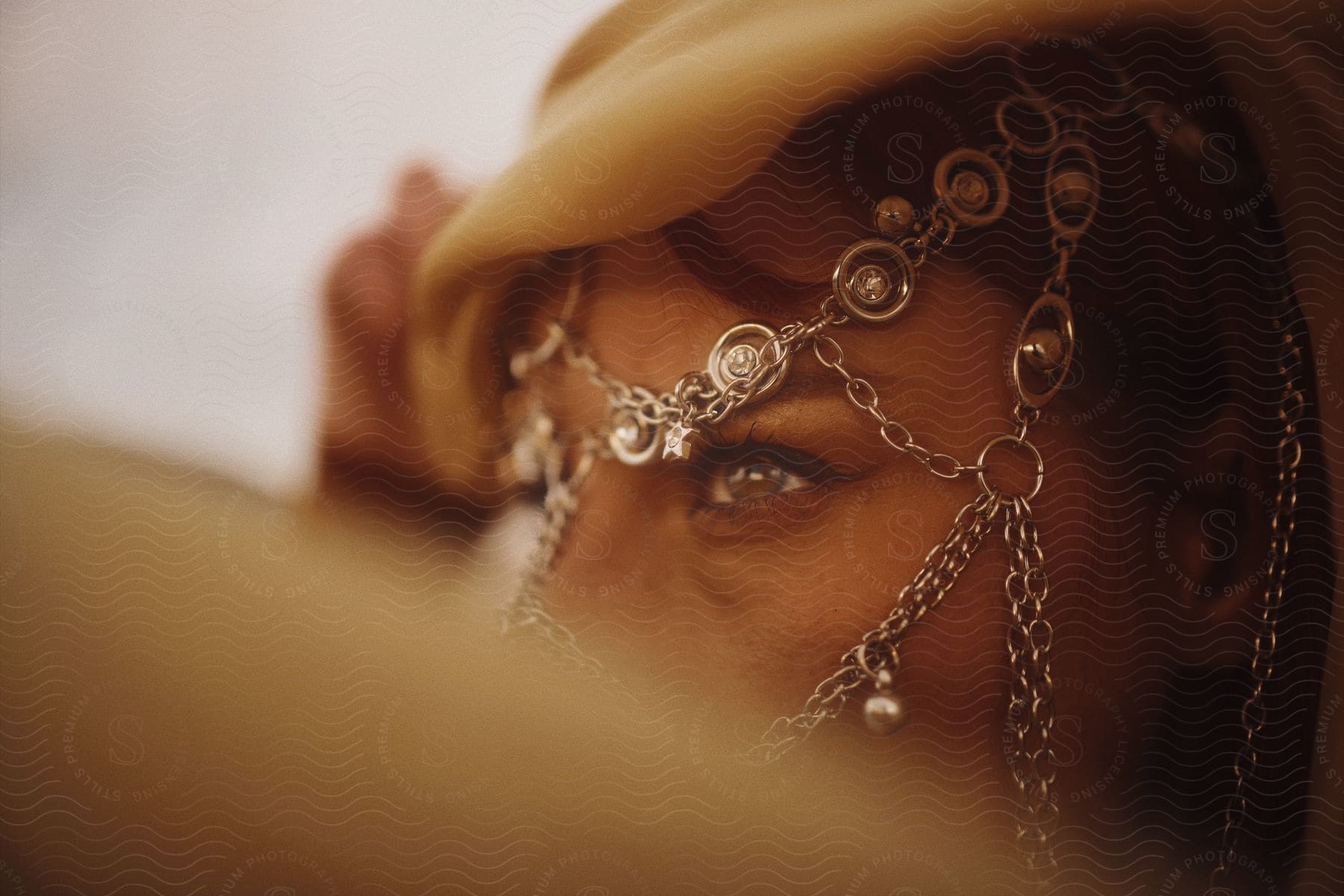 Close up of a woman's eye with chain jewelry partially obscuring her face, with a soft focus on the foreground.