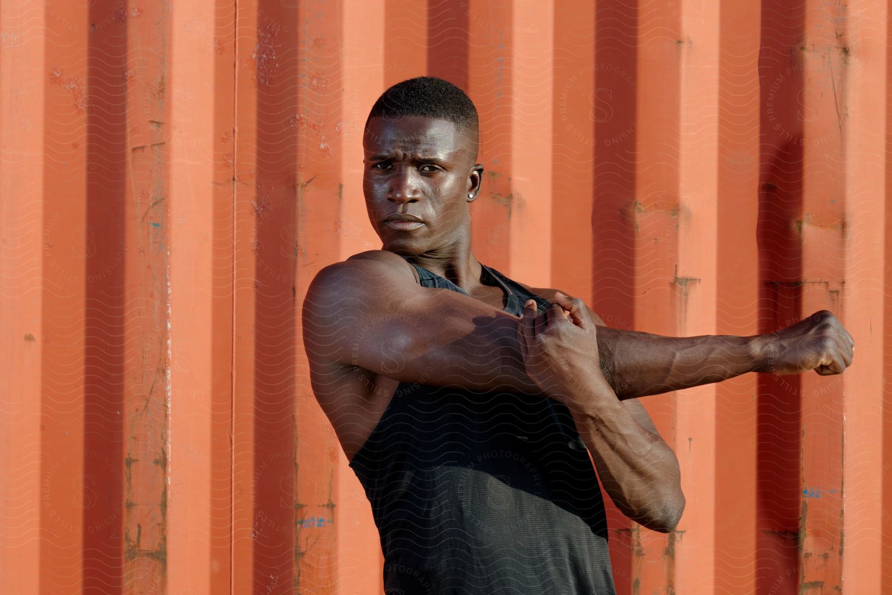 Man stretching his arm in front of an orange container.