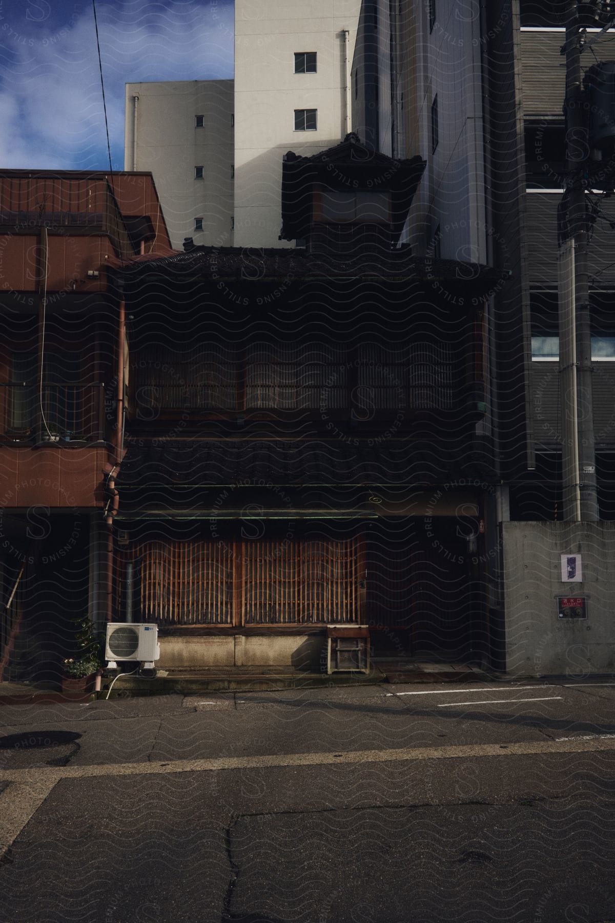 An older Japanese house between two apartment buildings.