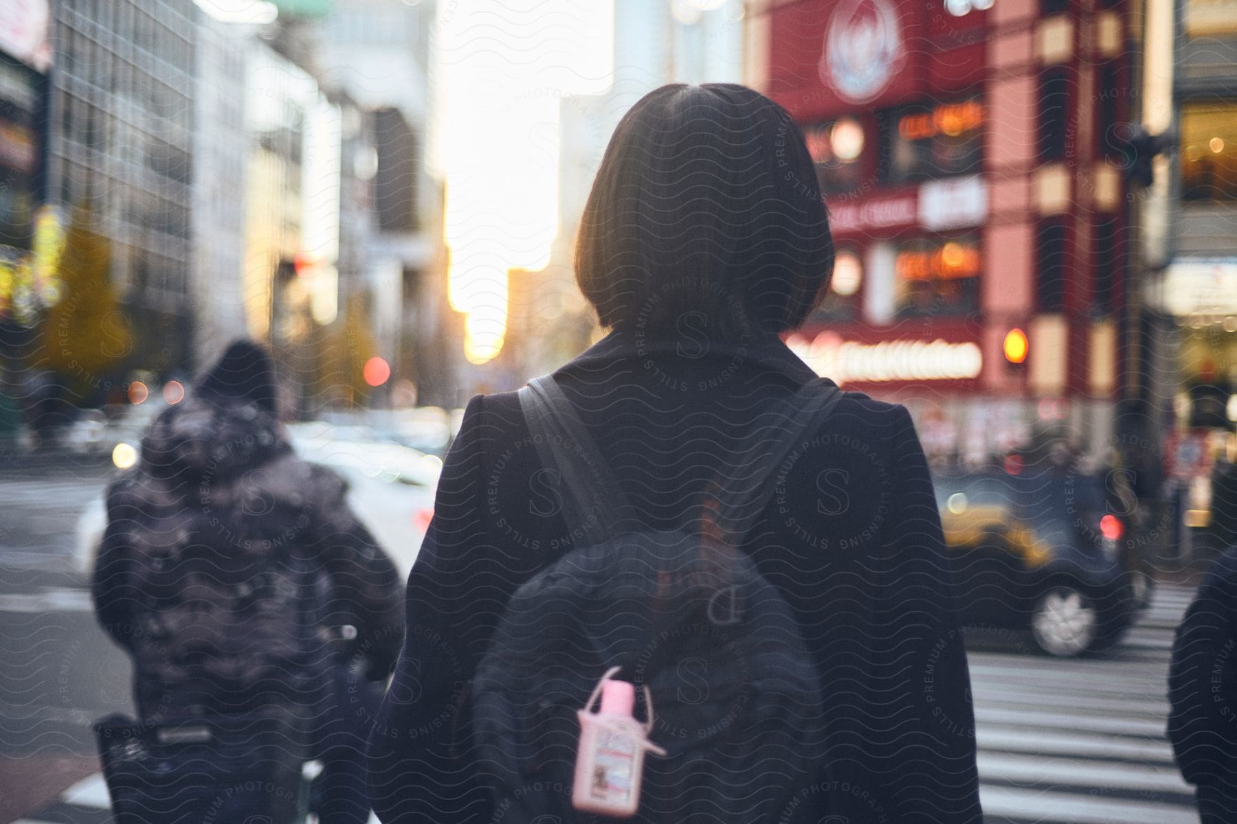 Woman wearing a backpack stands near a man on a bicycle on a downtown street