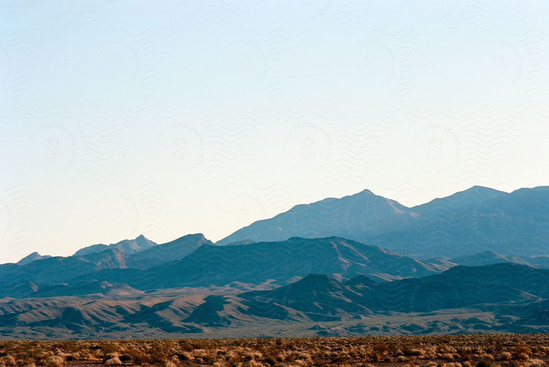 A serene desert landscape with distant mountains under a clear sky.