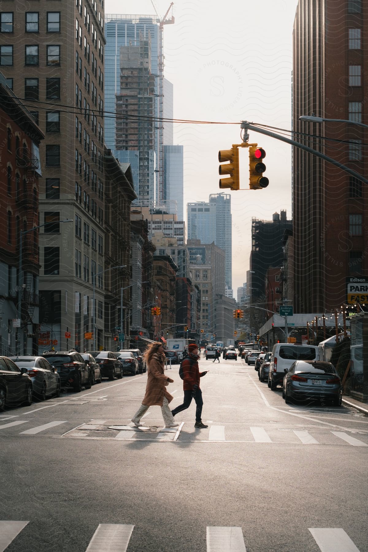 Two people crossing a New York City street in the crosswalk at a red light