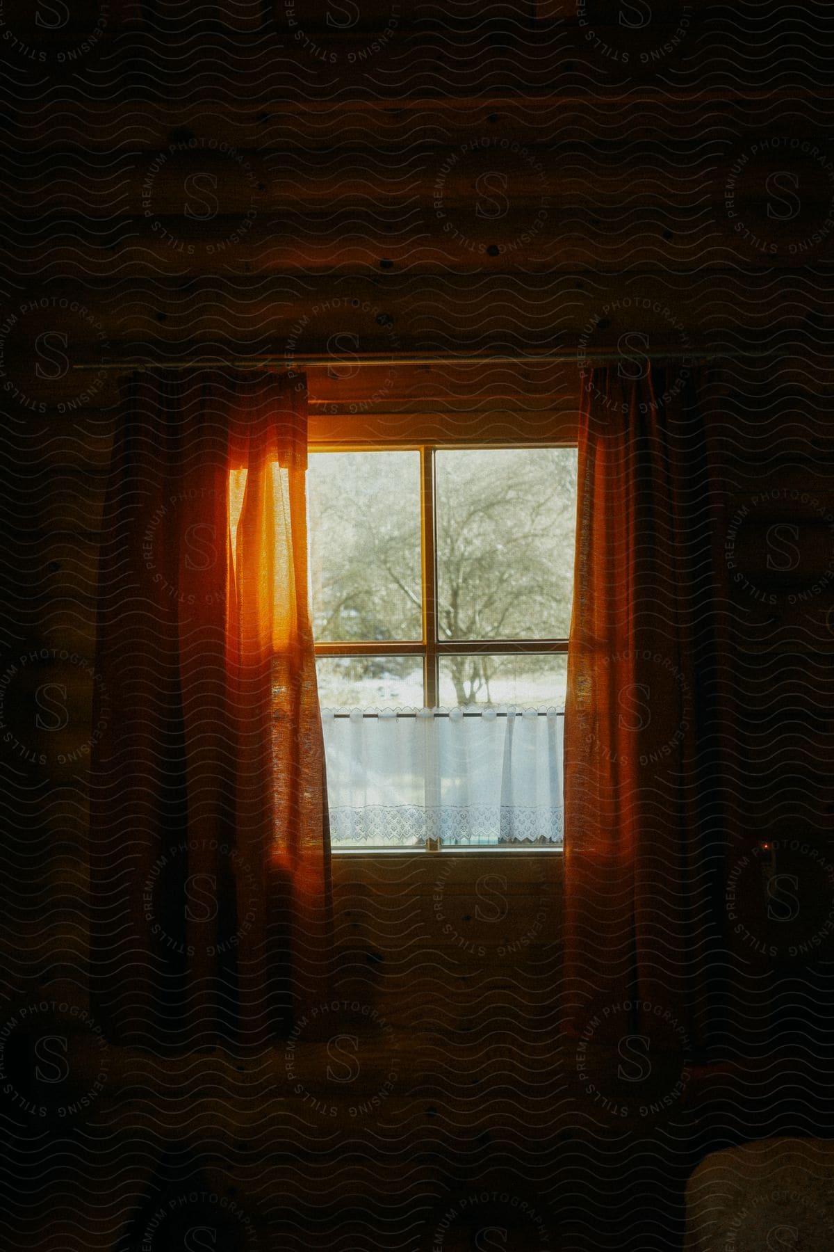 Interior of a wooden house with a view of a window with an open curtain and reflection of sunlight.