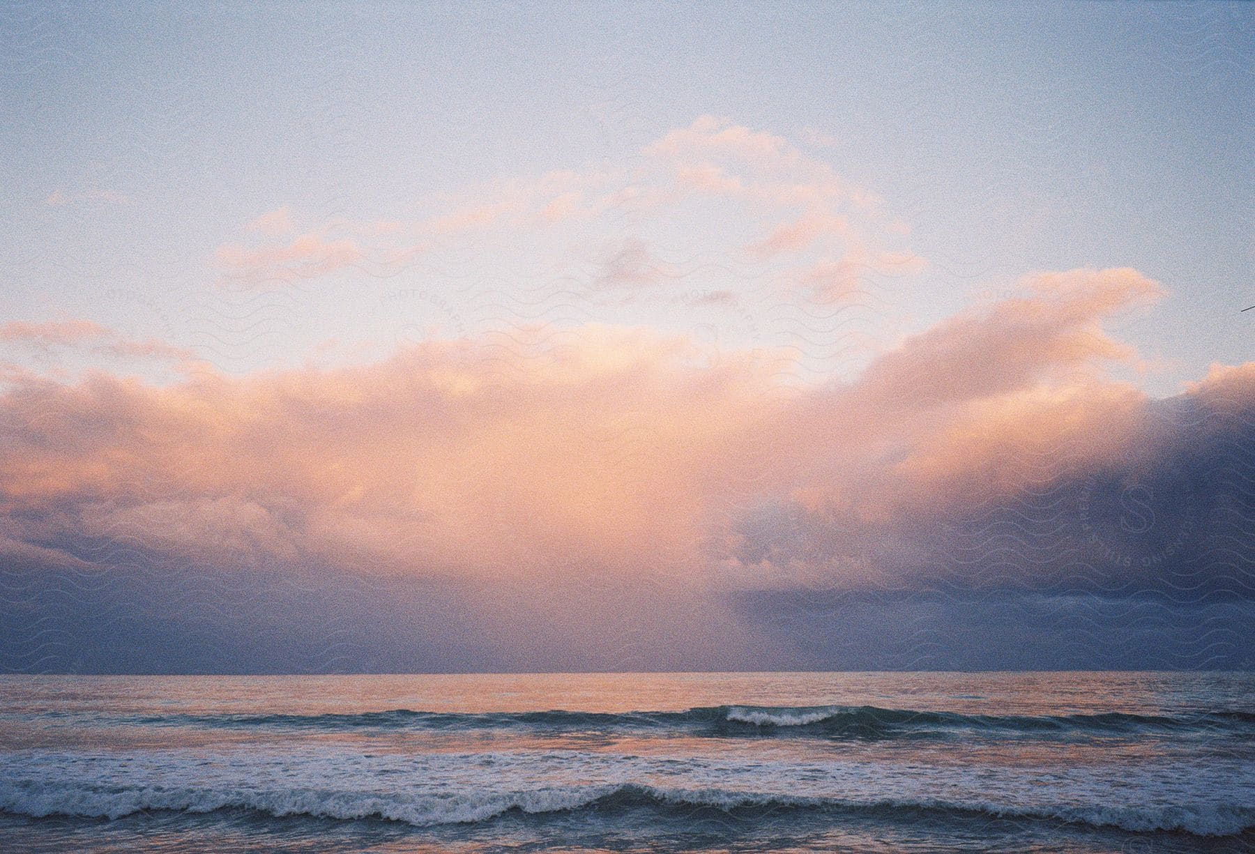 A serene beach scene at sunset, with gentle waves and a sky painted in pastel colors.