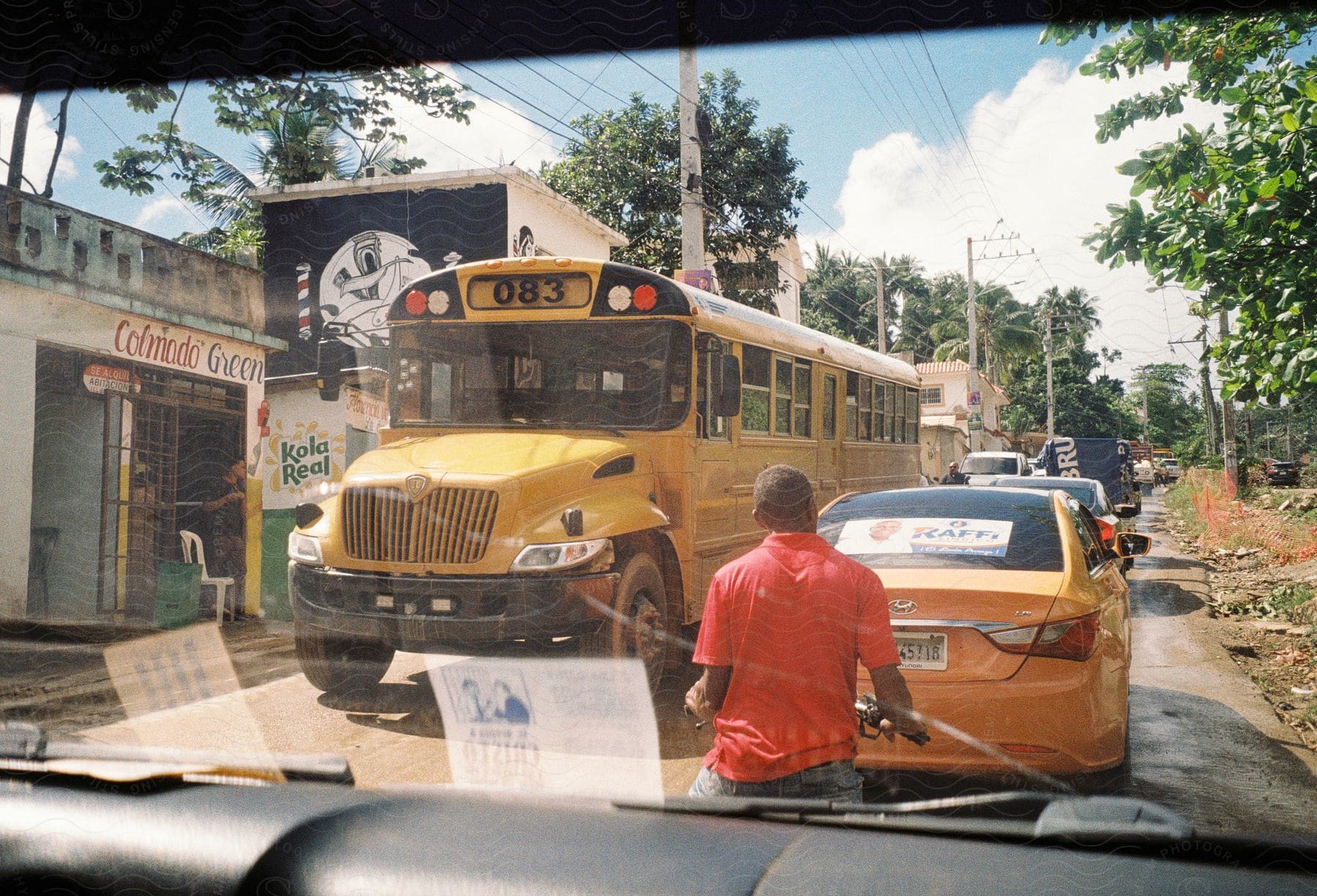 A vehicle is driving in the right lane of the road behind a bicycle, while a taxi passes by a yellow bus in the street.