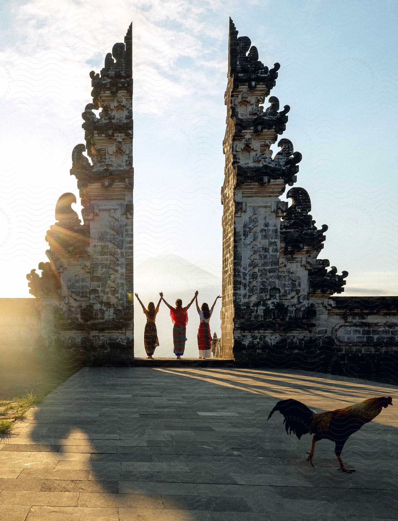 Three women with their backs and hands up at the Temple Of Penataran Agung Lempuyang.