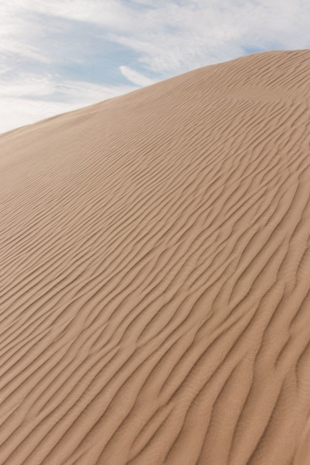 Dunes of a desert with blue sky marks during the day with clouds