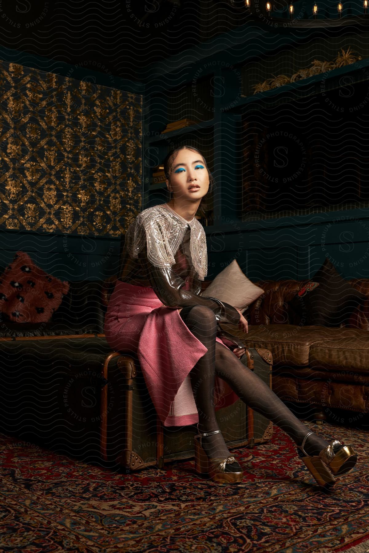 A model sitting on an old trunk in a room decorated with vintage furniture.