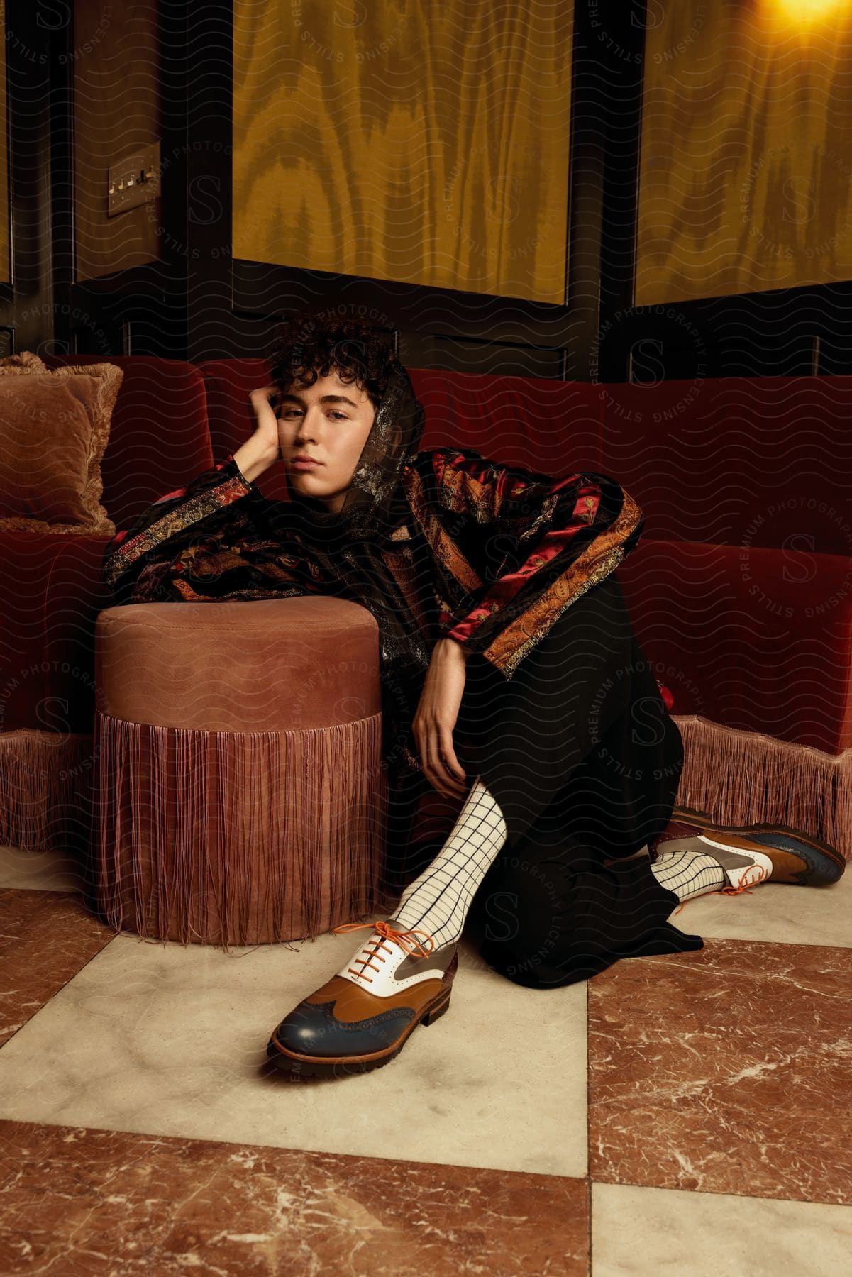 Woman sitting on the floor with her elbow resting on a stool with her head resting on her hand