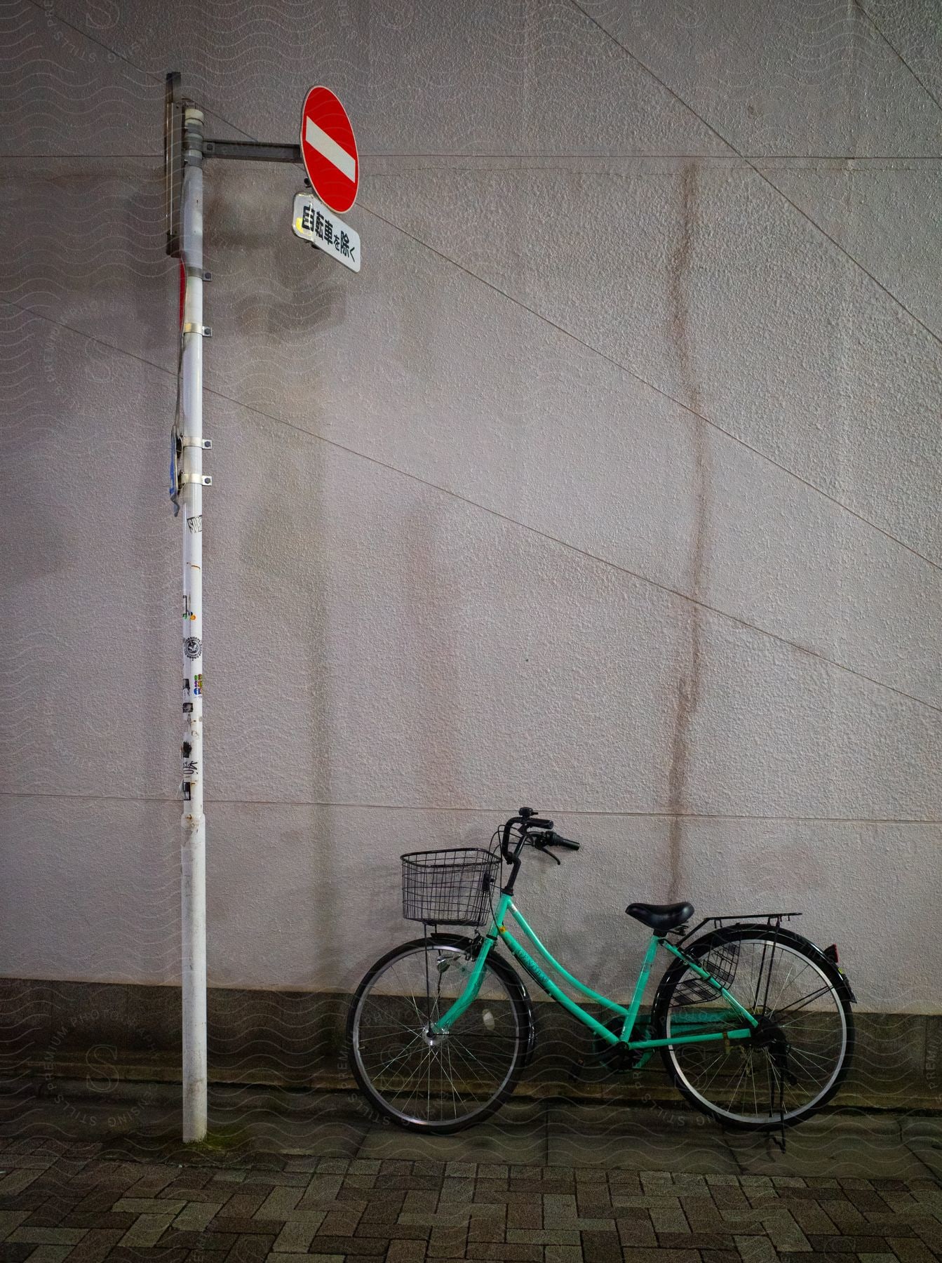 Asian signpost and next to it a bicycle leaning against a white wall.