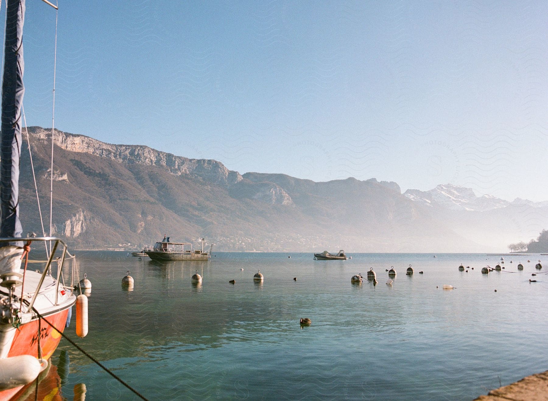 A view of some boats sitting on a lake with mountains behind it.